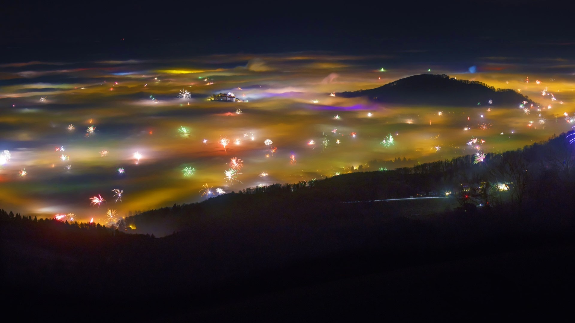 Fireworks over a foggy valley at night HD Wallpaper