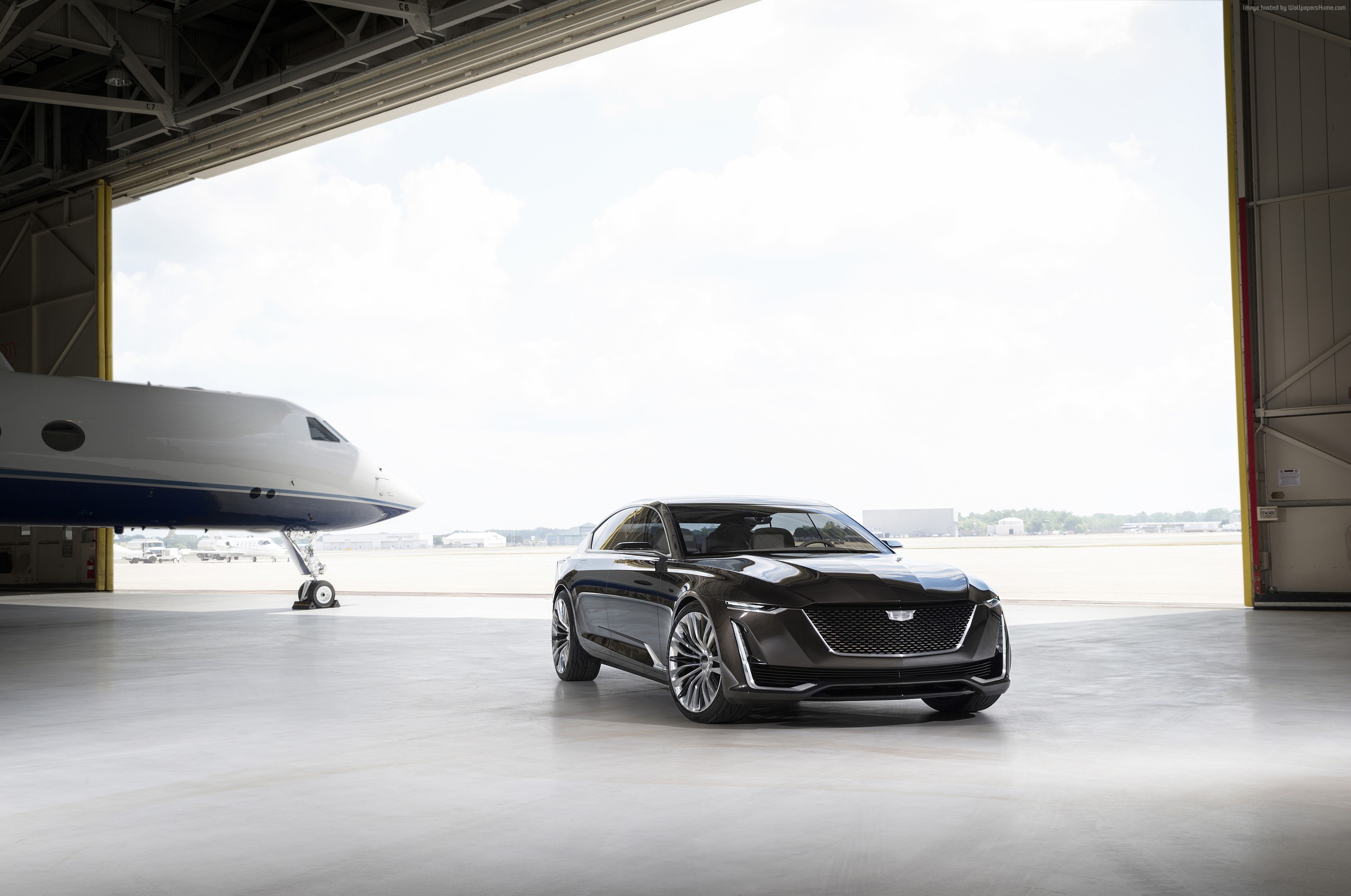 Cadillac Escala concept sedan in a hangar with a private jet HD Wallpaper