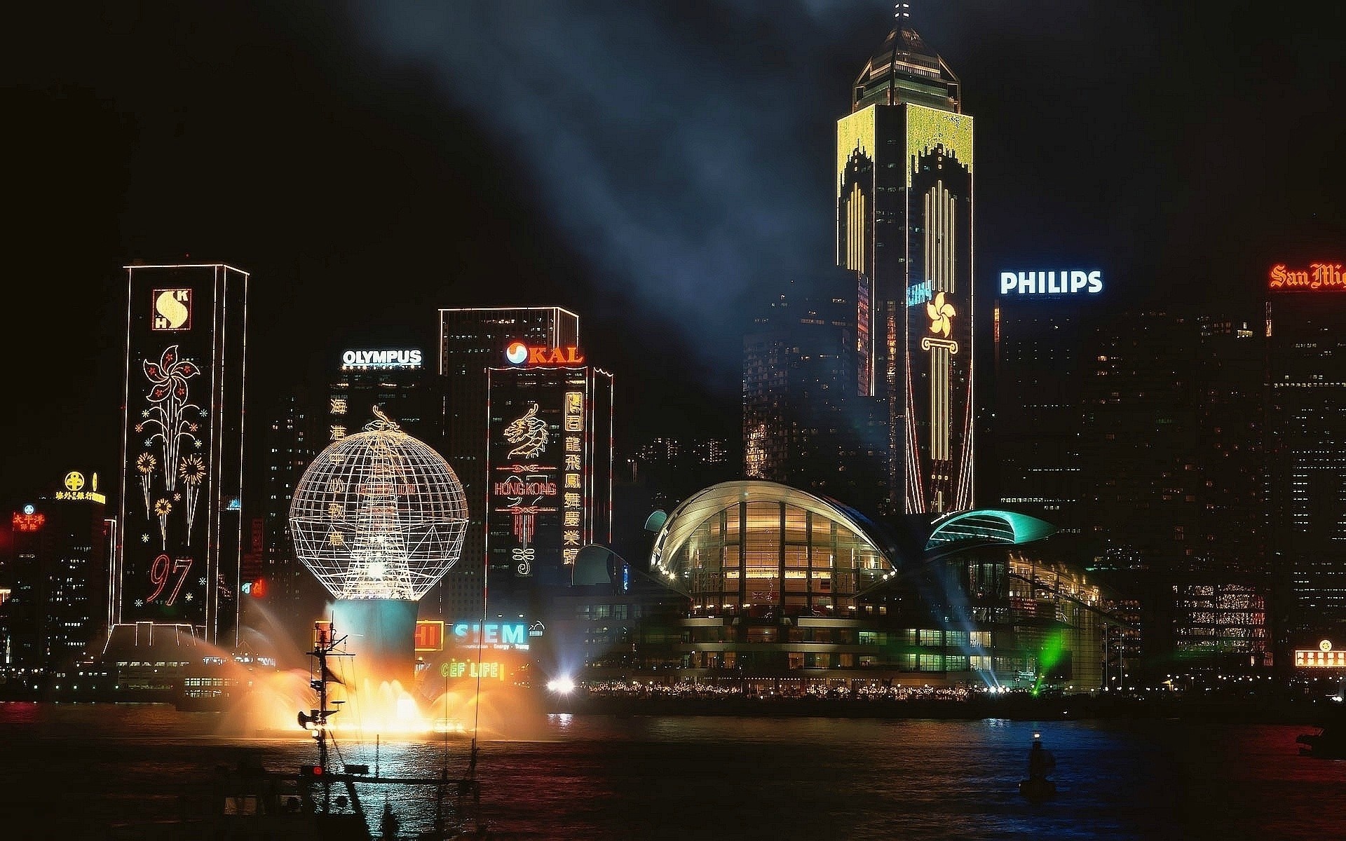 Hong Kong skyline at night with illuminated buildings and water feature HD Wallpaper