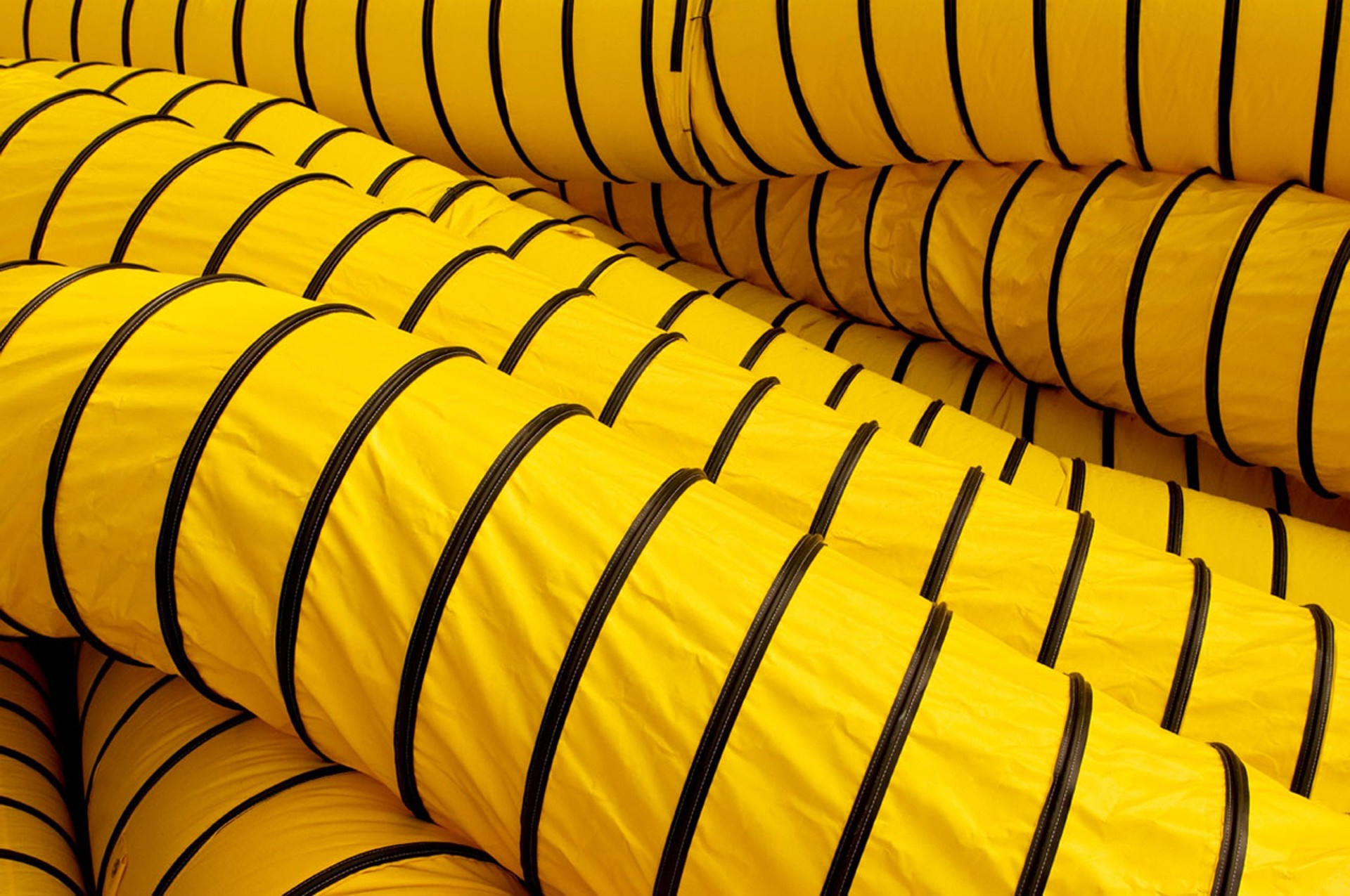 Stacked yellow flexible ventilation ducts with black stripes HD Wallpaper