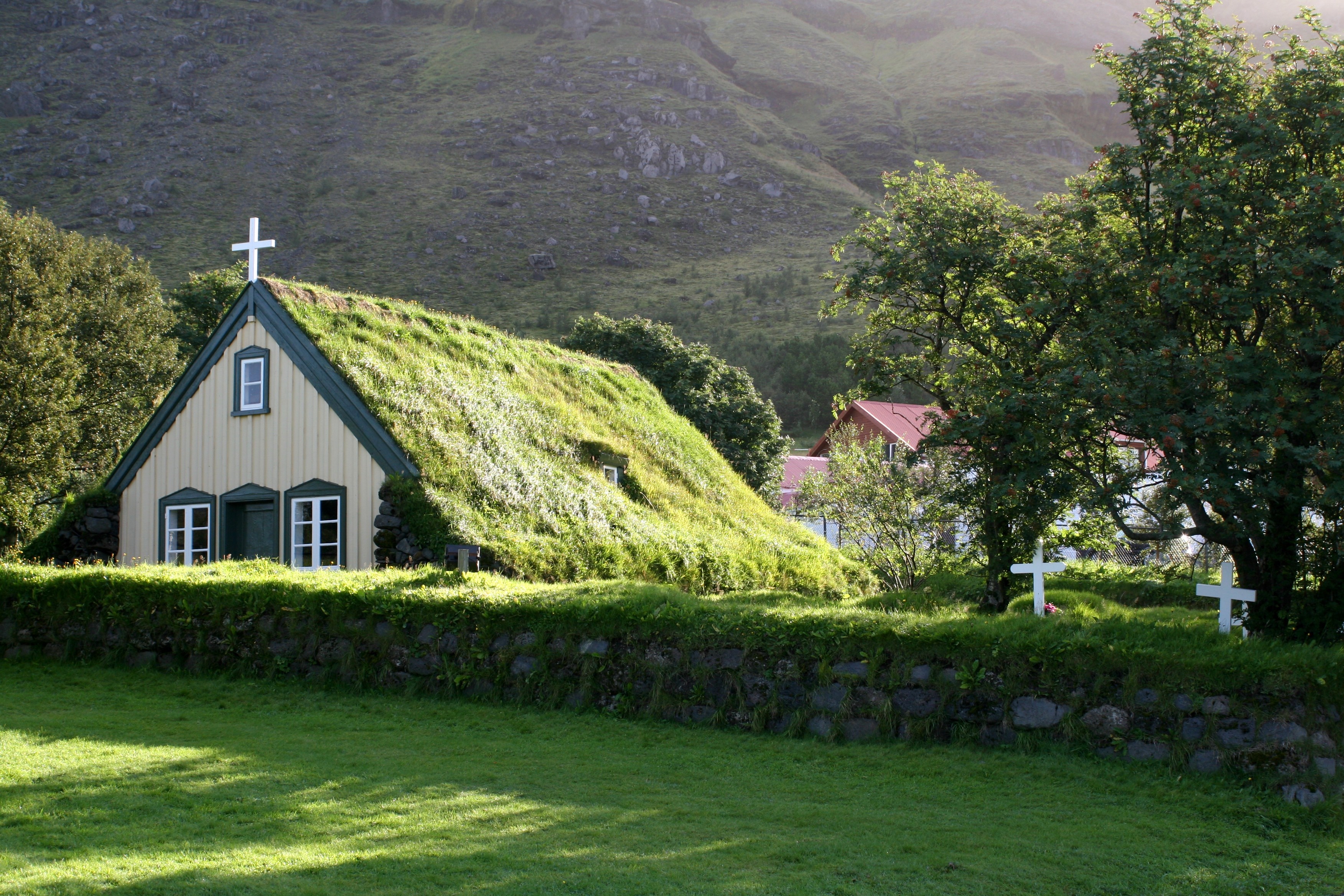 Grass-roofed church with crosses in a rural landscape HD Wallpaper