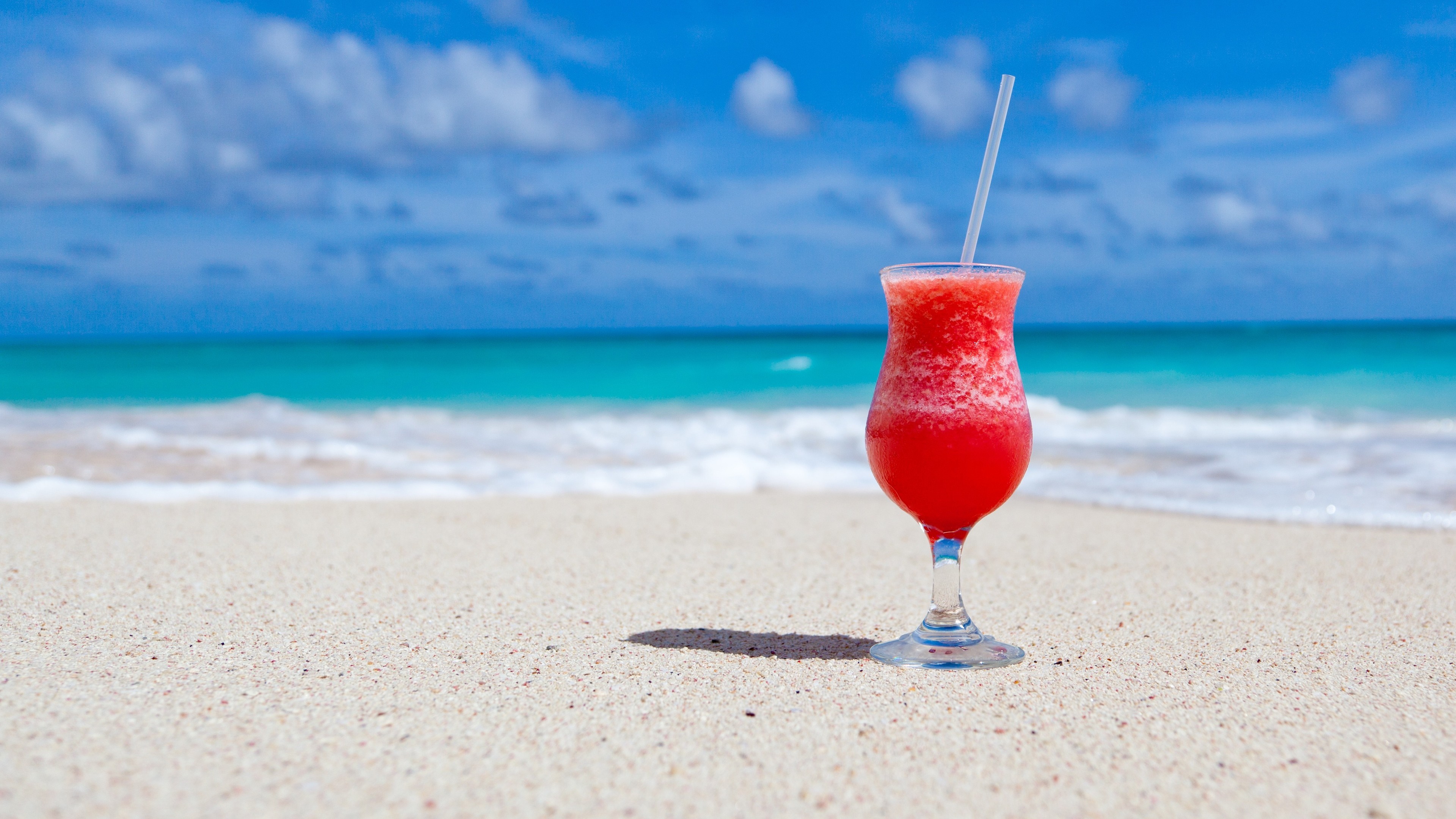 Red cocktail on a sandy beach with ocean background HD Wallpaper