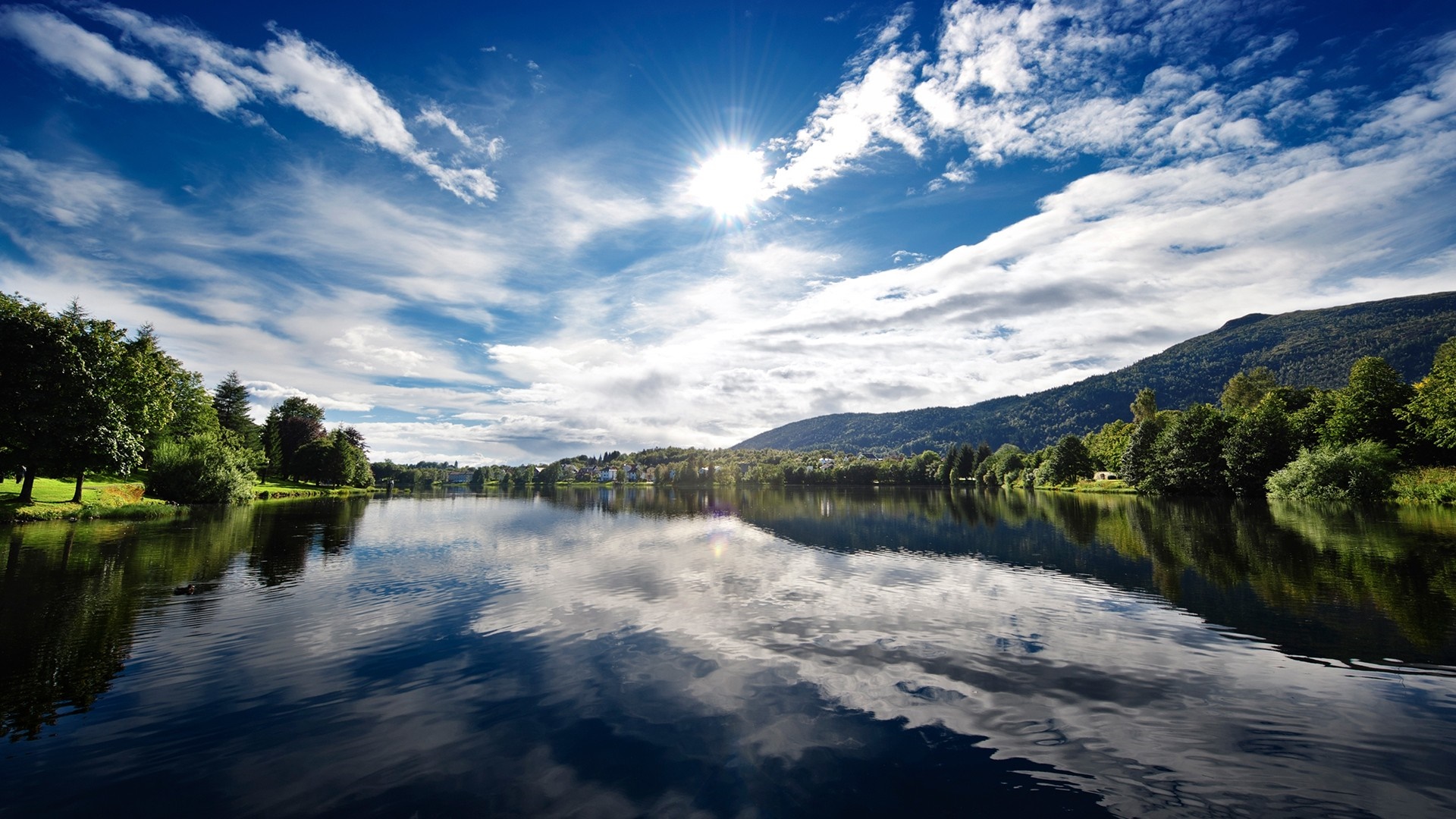 Lake reflection with mountains and sunlit sky HD Wallpaper
