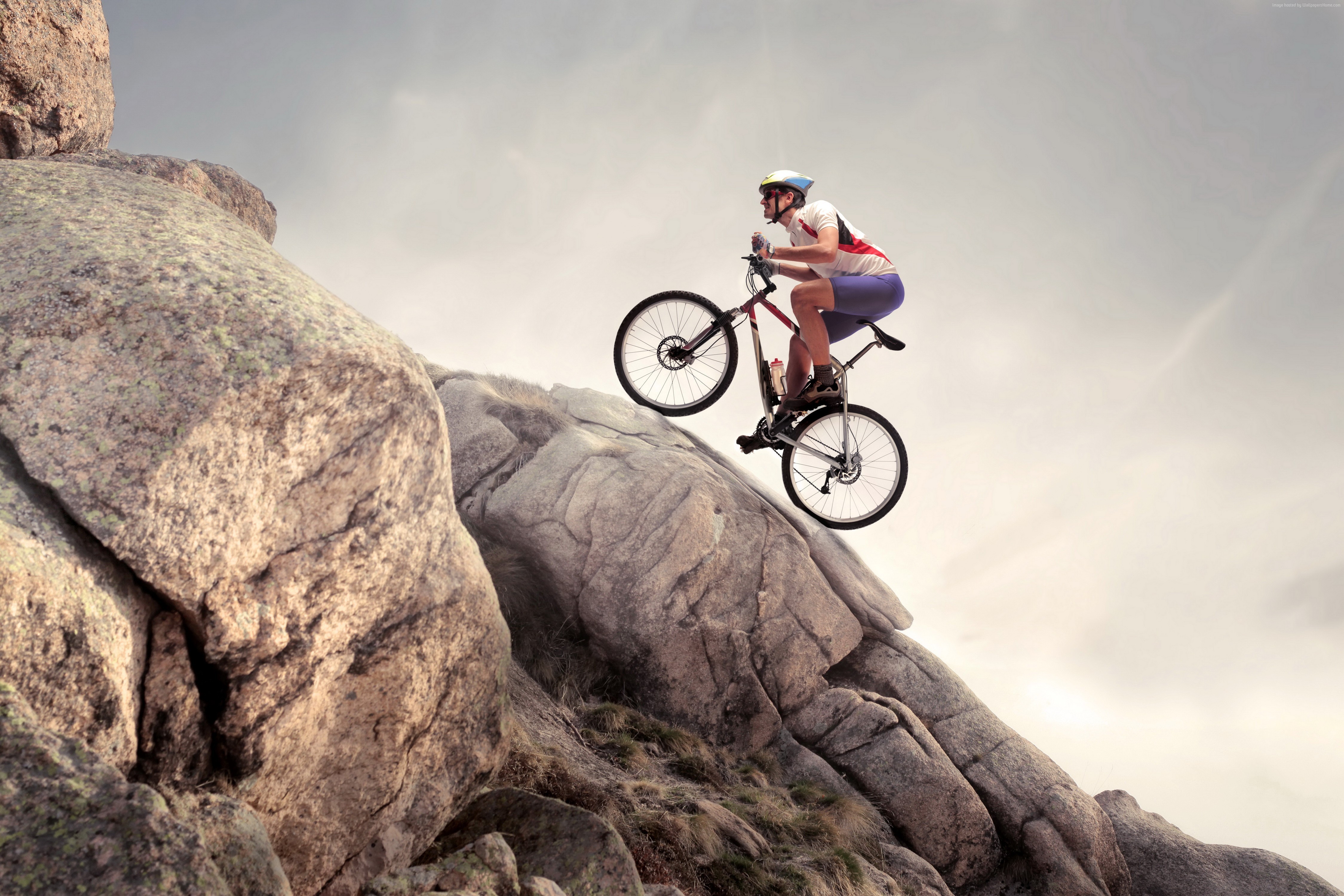 Mountain biker performing a stunt on a rocky slope HD Wallpaper