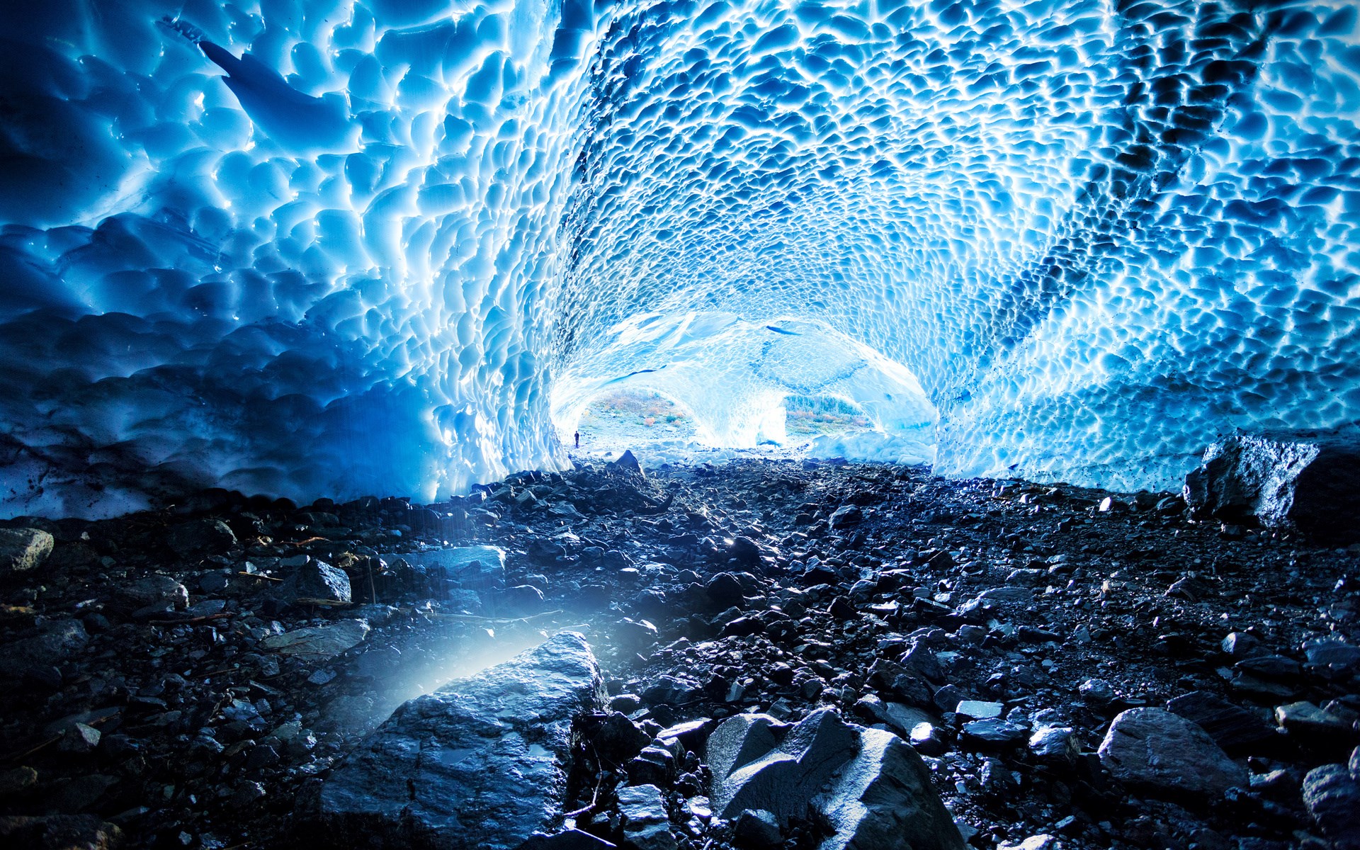 Ice cave with rocky floor and person HD Wallpaper