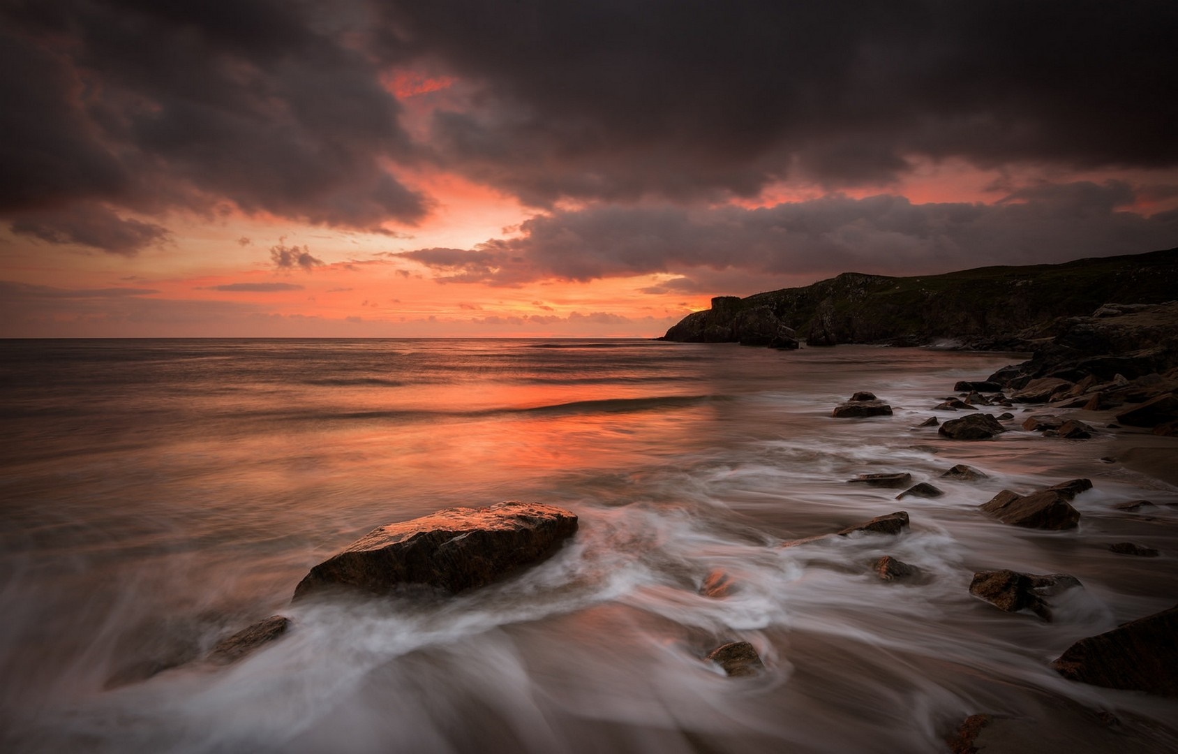 Sunset over a rocky shore with waves HD Wallpaper