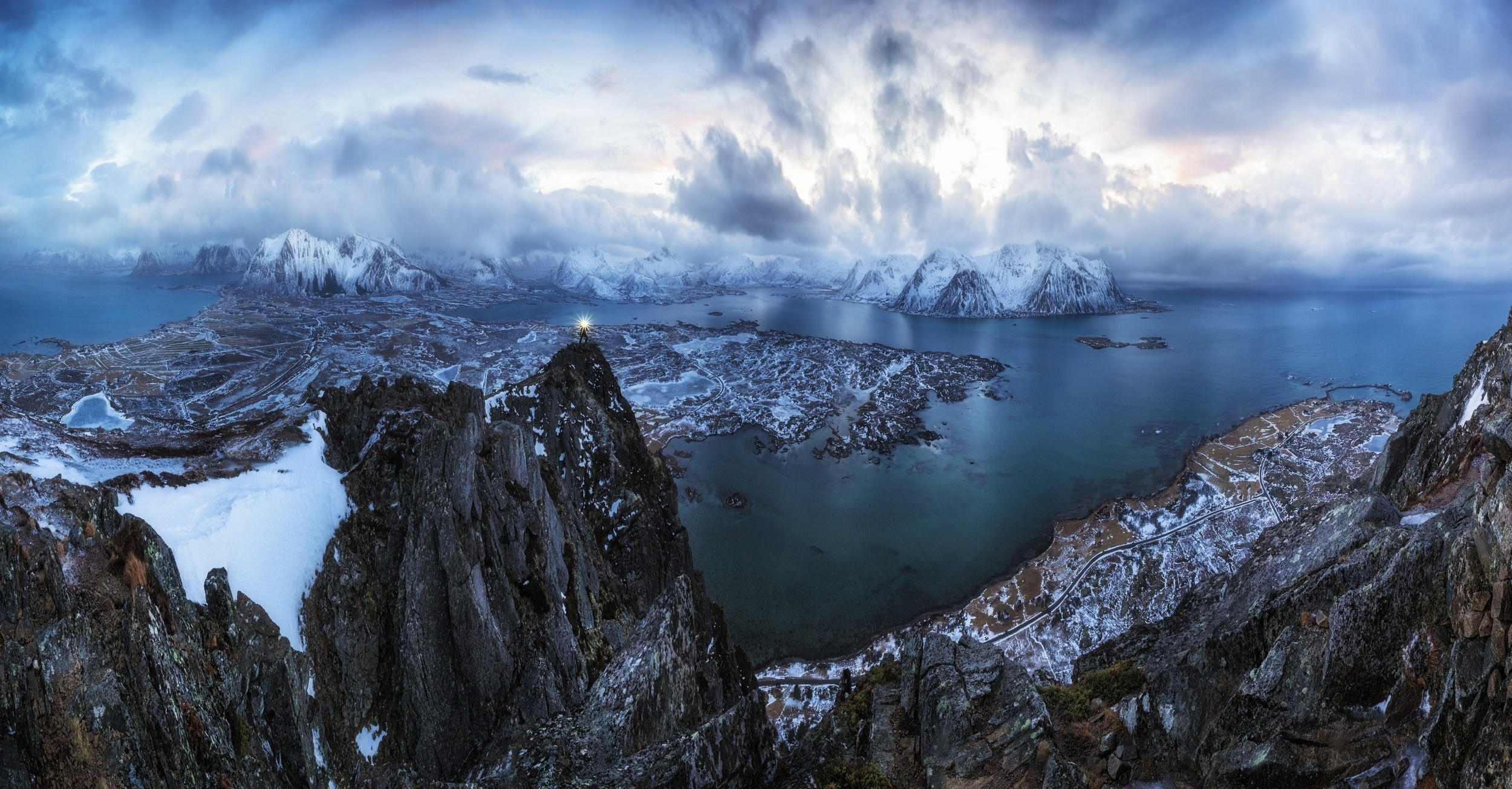Man with torch on mountain summit overlooking Lofoten Islands HD Wallpaper