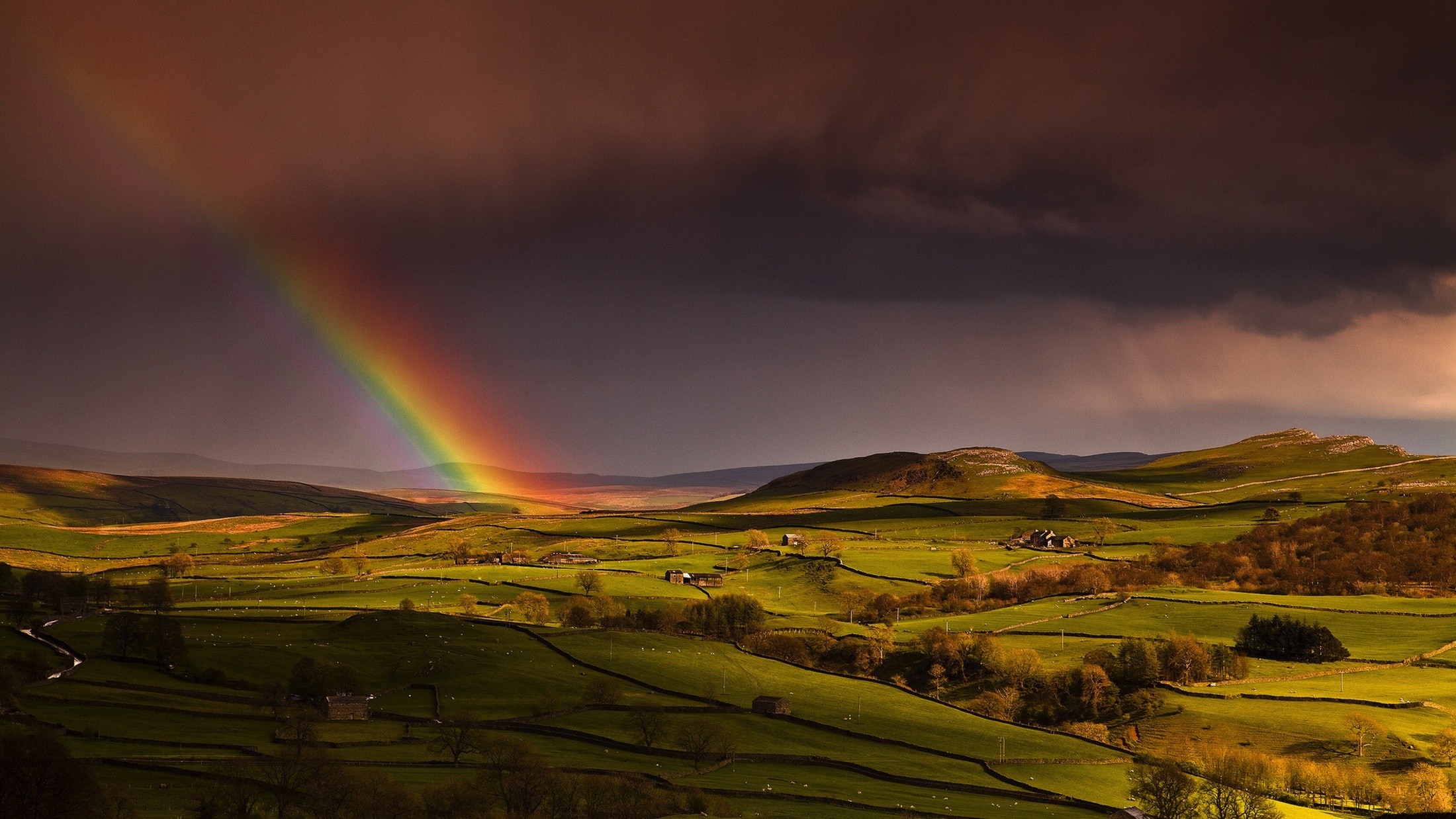 Rainbow over rolling green hills at sunset HD Wallpaper