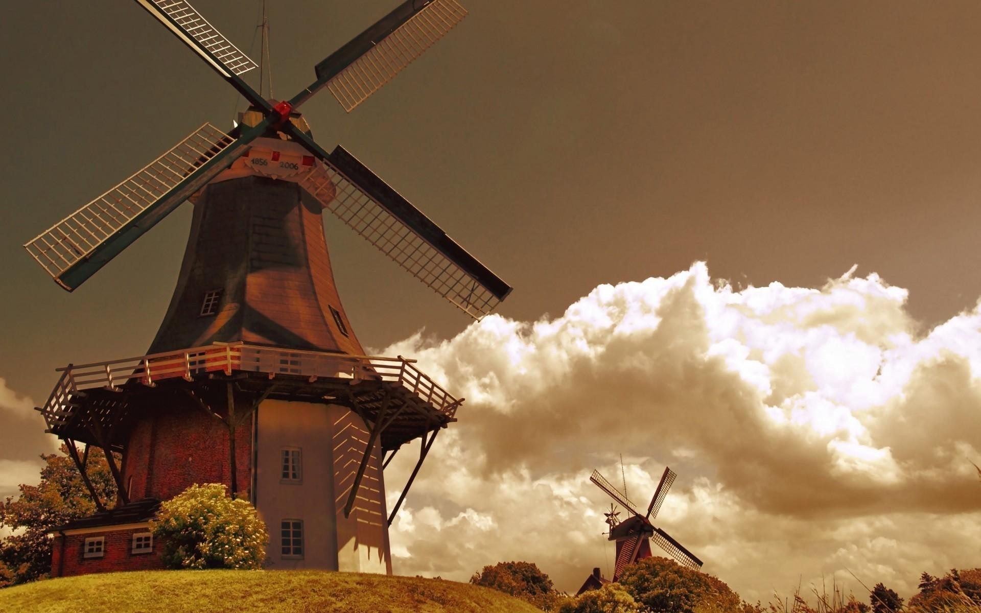 Two windmills on a grassy hill with clouds HD Wallpaper