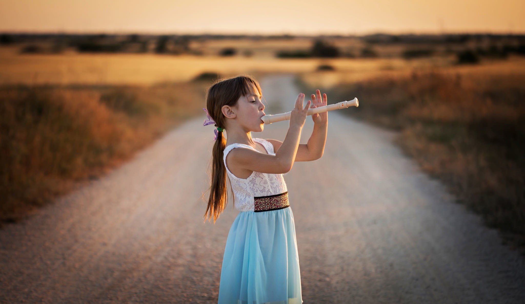 Girl playing recorder on a dirt road at sunset HD Wallpaper