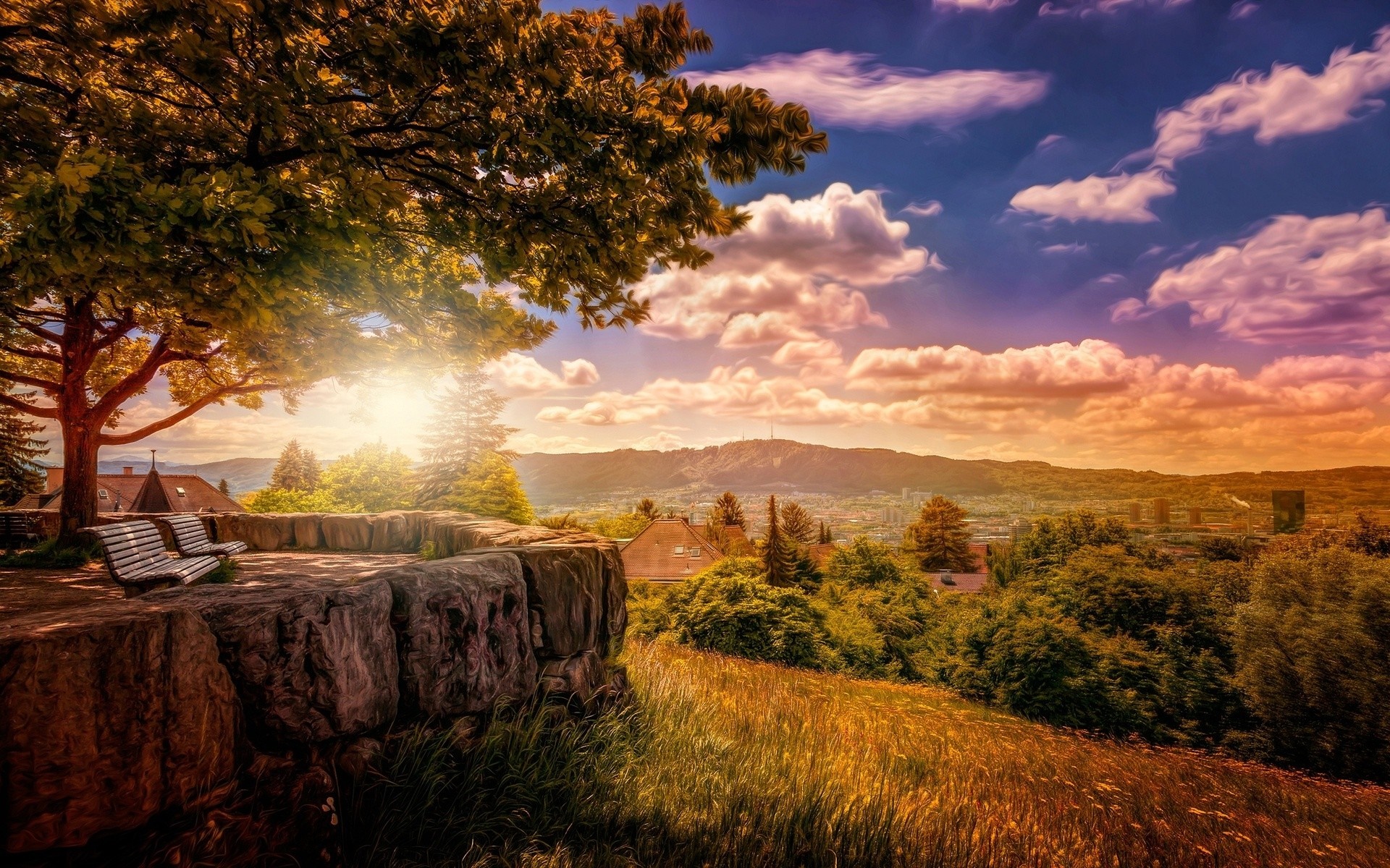 Scenic overlook with benches and a distant town at sunset HD Wallpaper