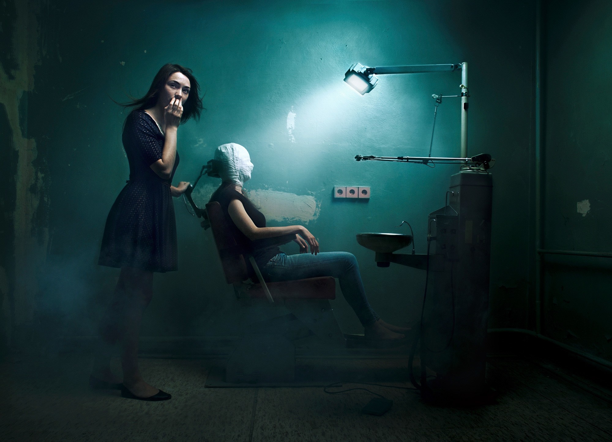 Two women in a dark, eerie room with dental equipment HD Wallpaper