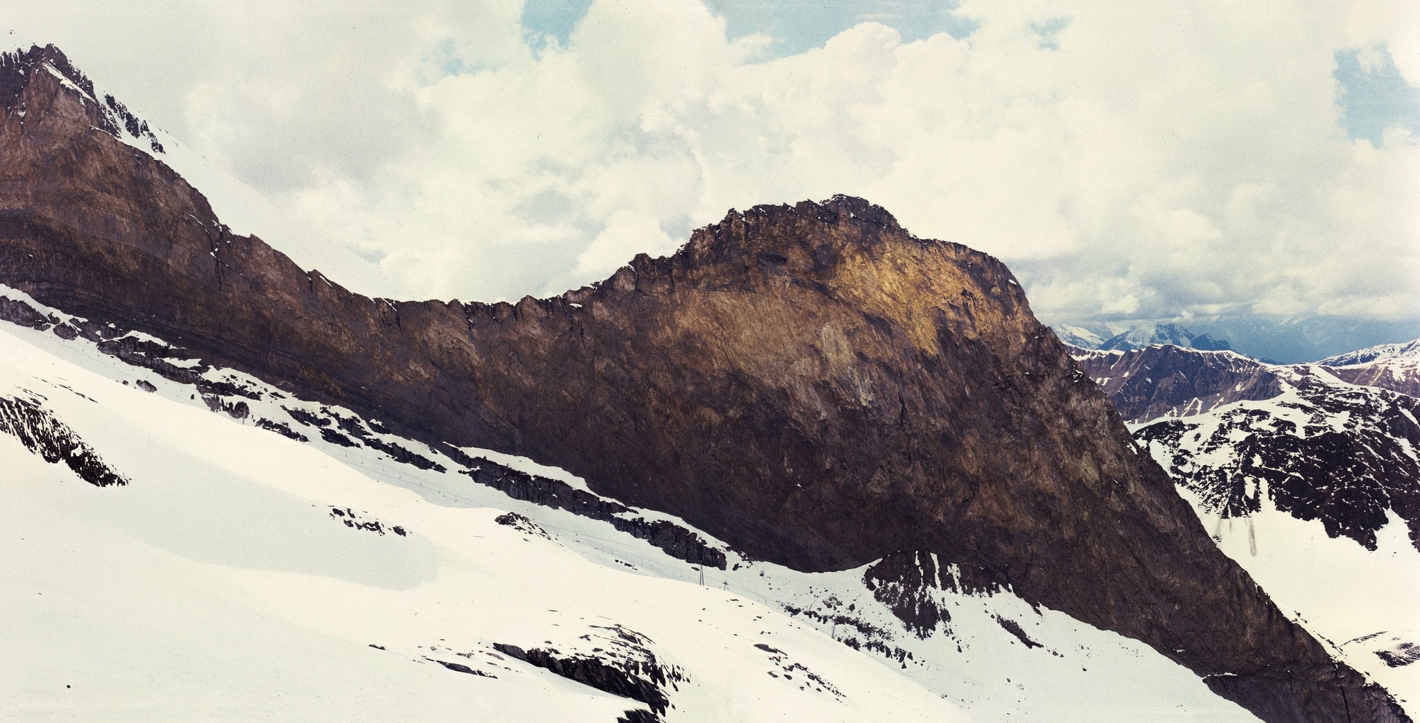 Snow-covered mountains under a cloudy sky HD Wallpaper