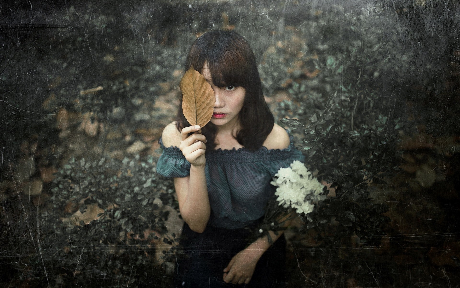 Woman holding a leaf in front of her eye with flowers HD Wallpaper