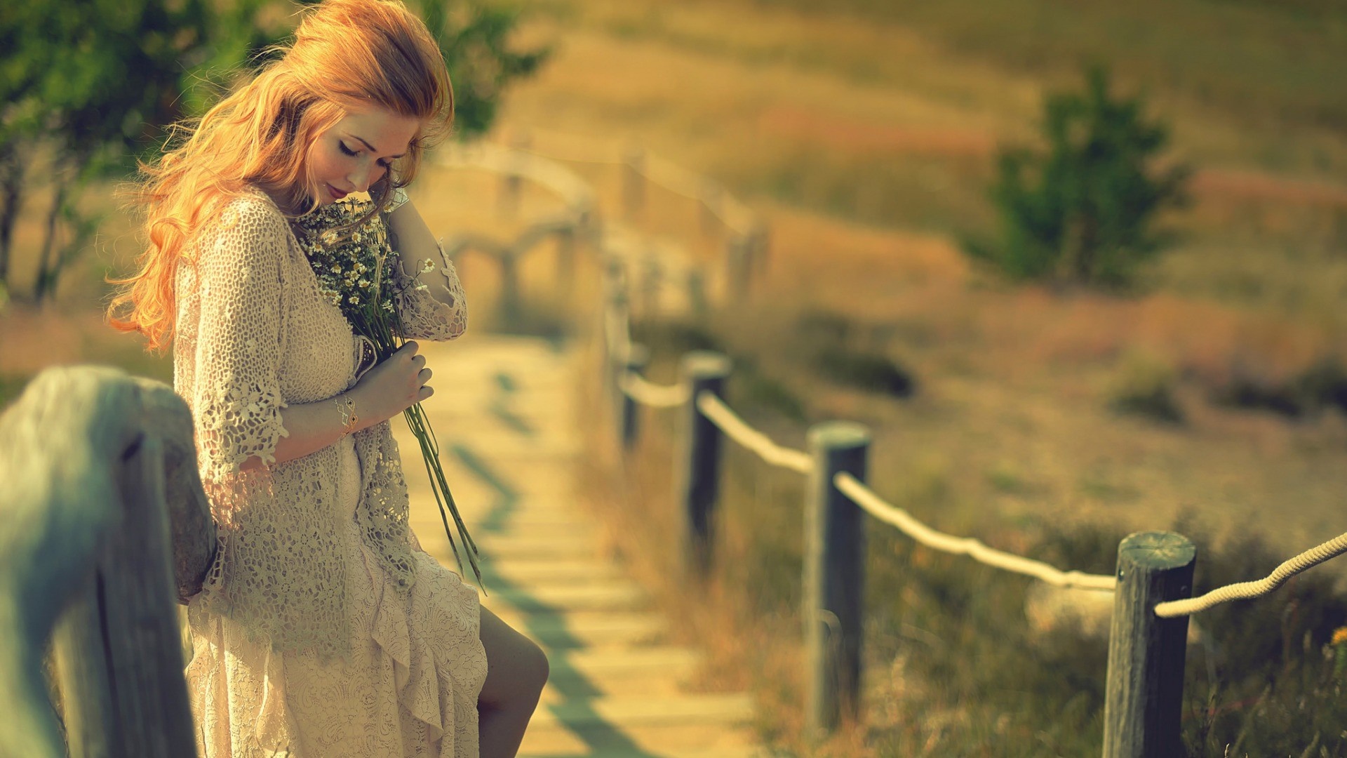 Woman with red hair holding flowers on a wooden path HD Wallpaper