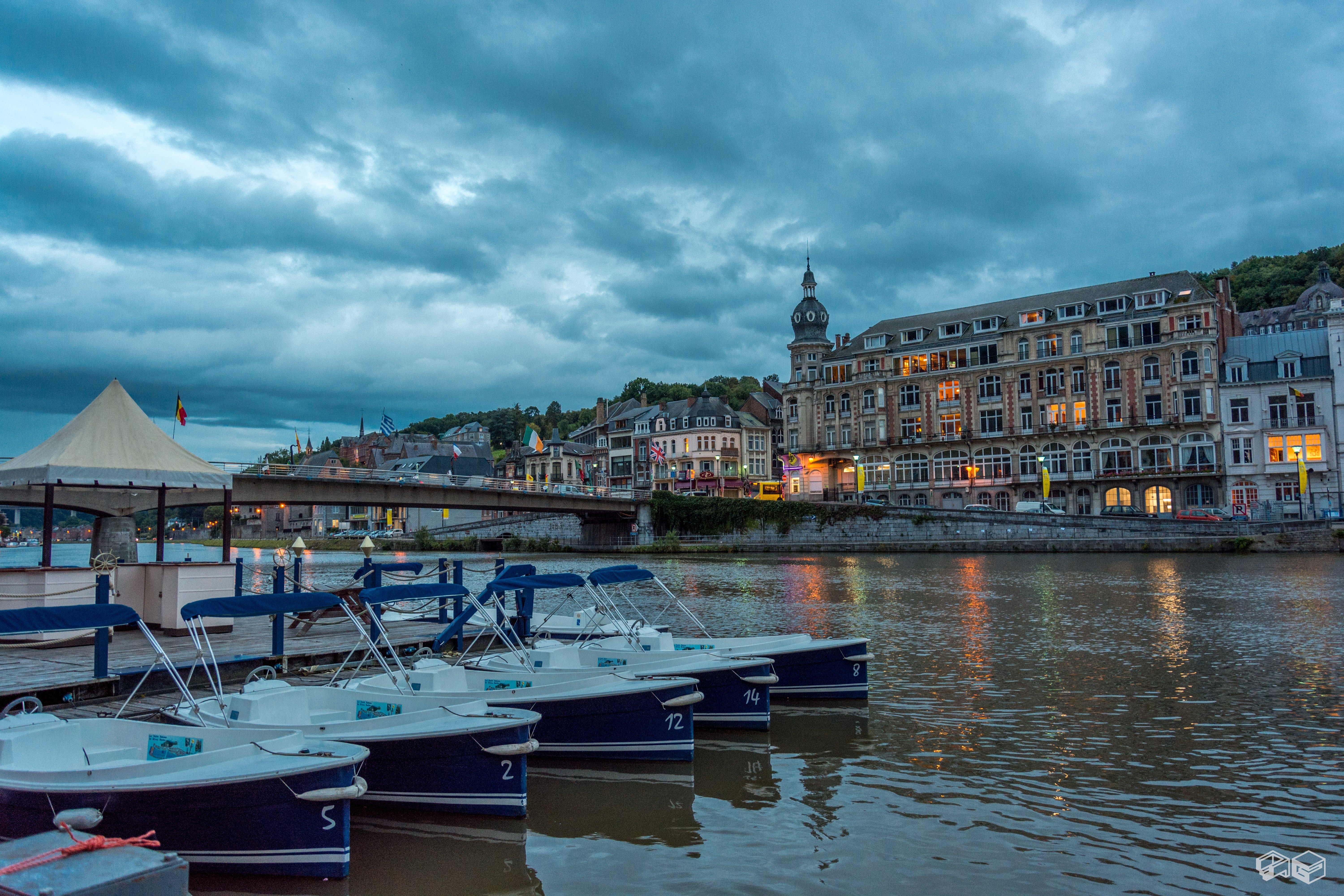Boats docked on a river in Dinant, Belgium at dusk HD Wallpaper
