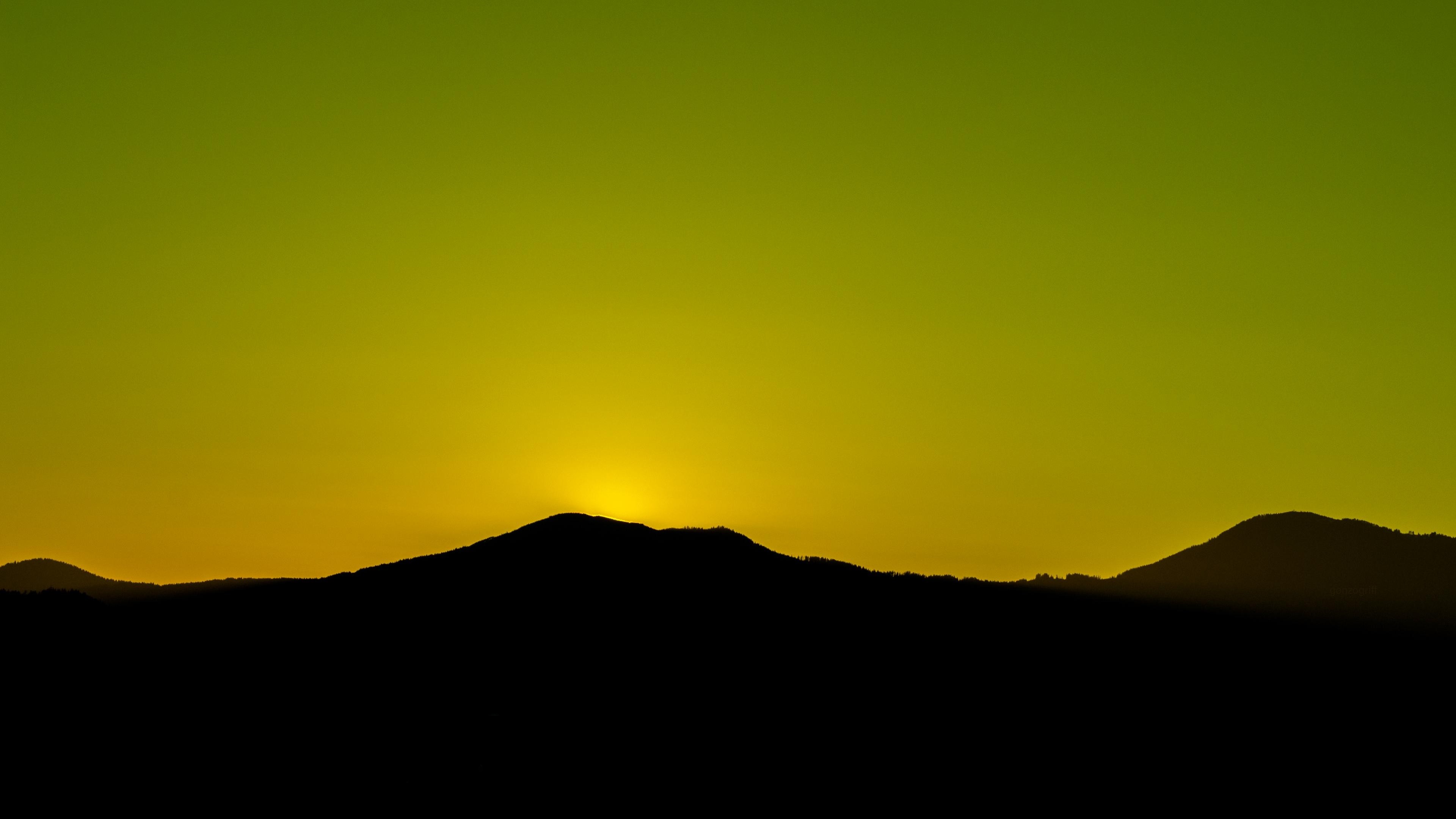 Silhouette of mountains at sunset with yellow sky HD Wallpaper