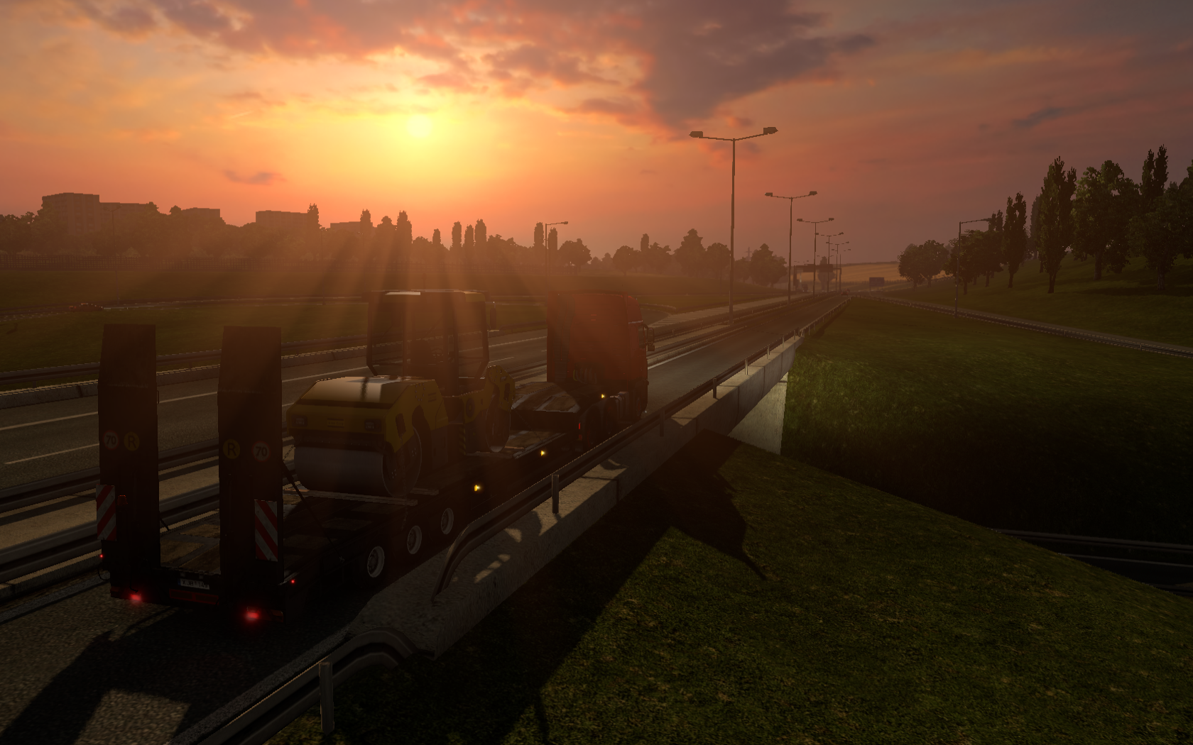 Truck carrying a roller on a highway at sunset HD Wallpaper