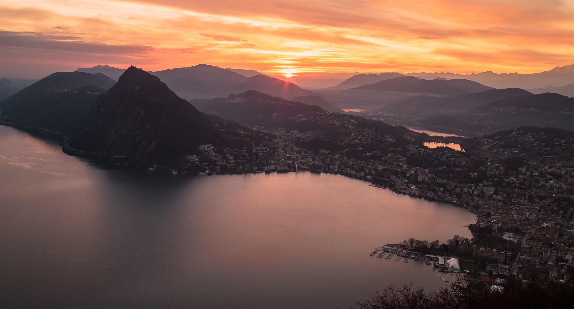 Sunset over mountains and lake with city HD Wallpaper