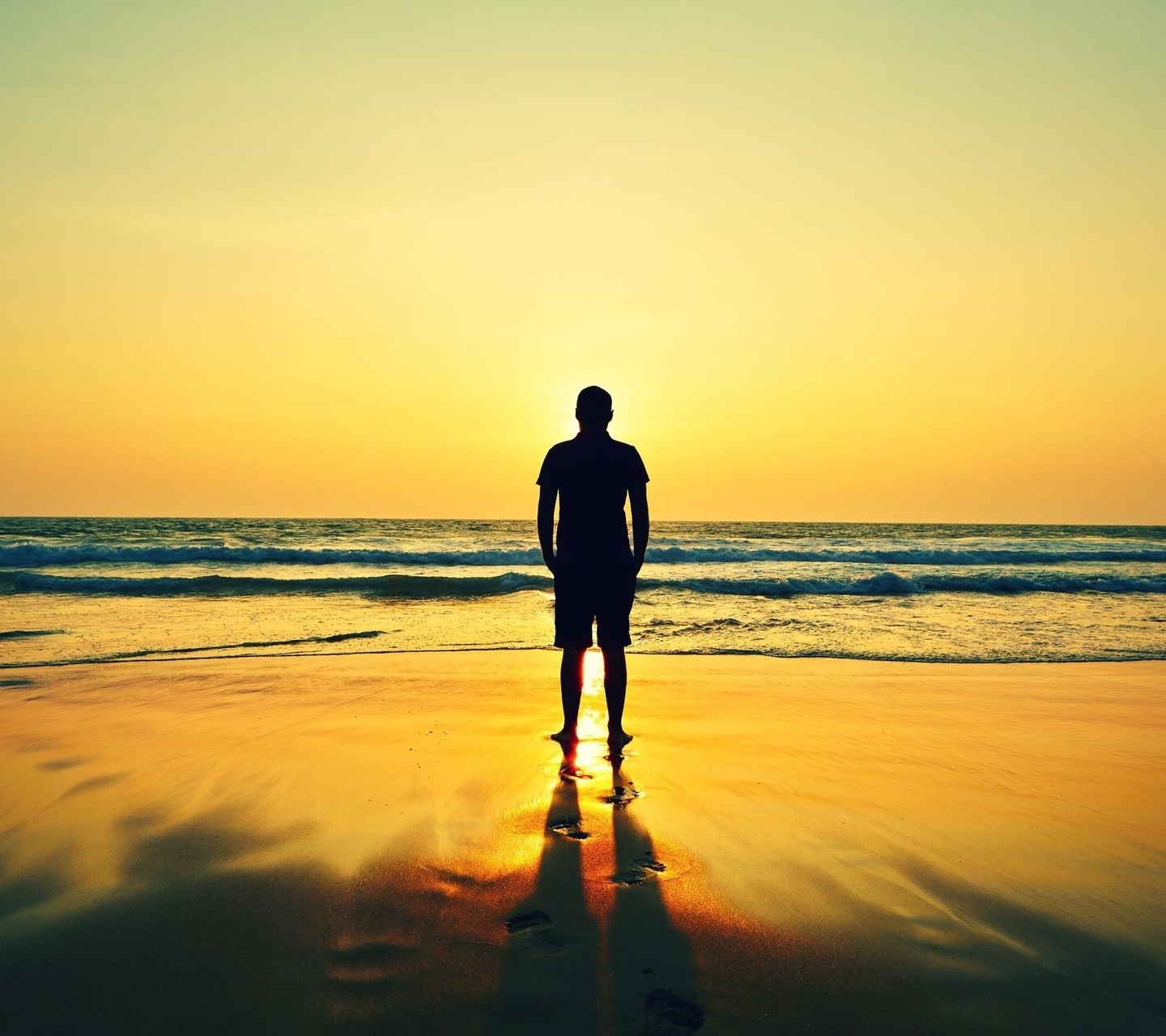 Man silhouetted against sunset on a beach HD Wallpaper