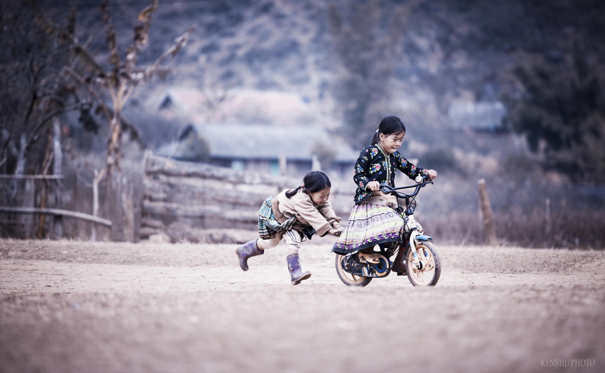 Two children playing with a bicycle outdoors HD Wallpaper