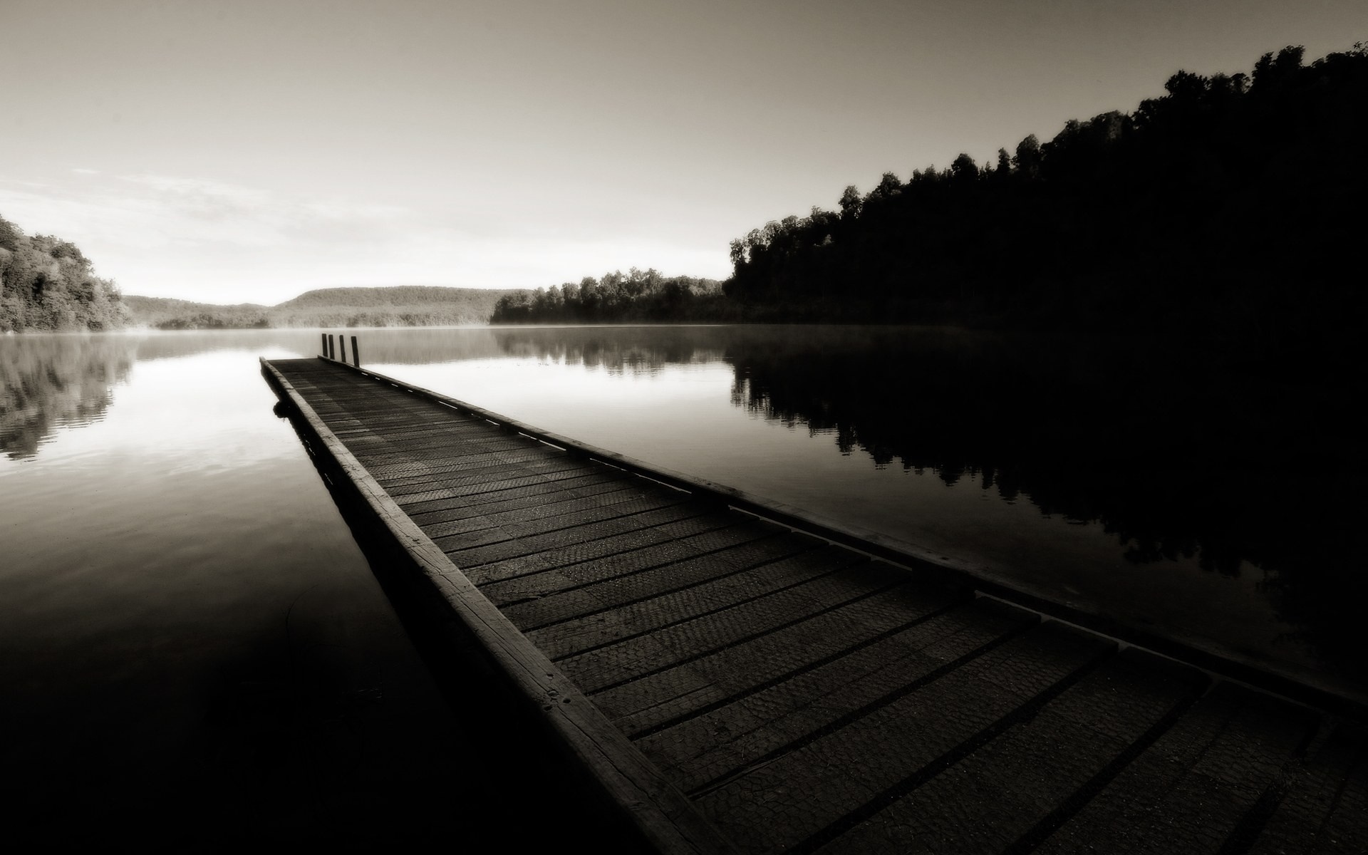 Monochrome image of a wooden dock on a misty lake at dawn HD Wallpaper
