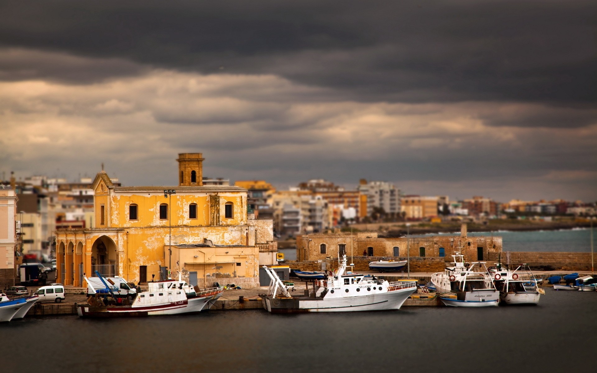 Boats docked in a harbor with a yellow building and cityscape HD Wallpaper