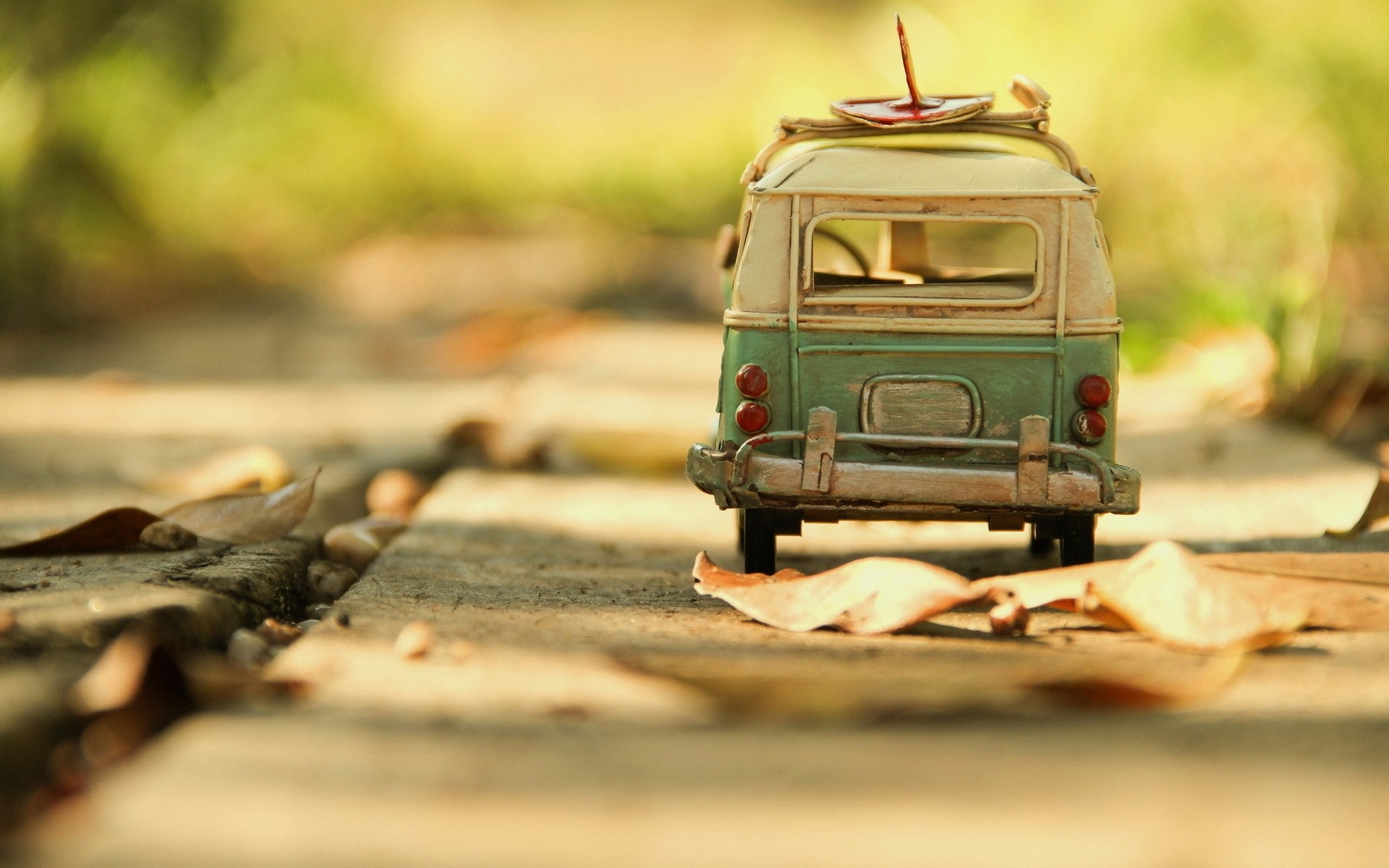 Toy van with surfboard on a path with leaves HD Wallpaper