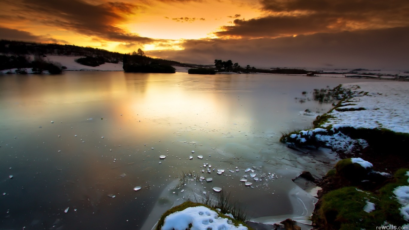 Frozen lake at sunset with snow-covered shore HD Wallpaper