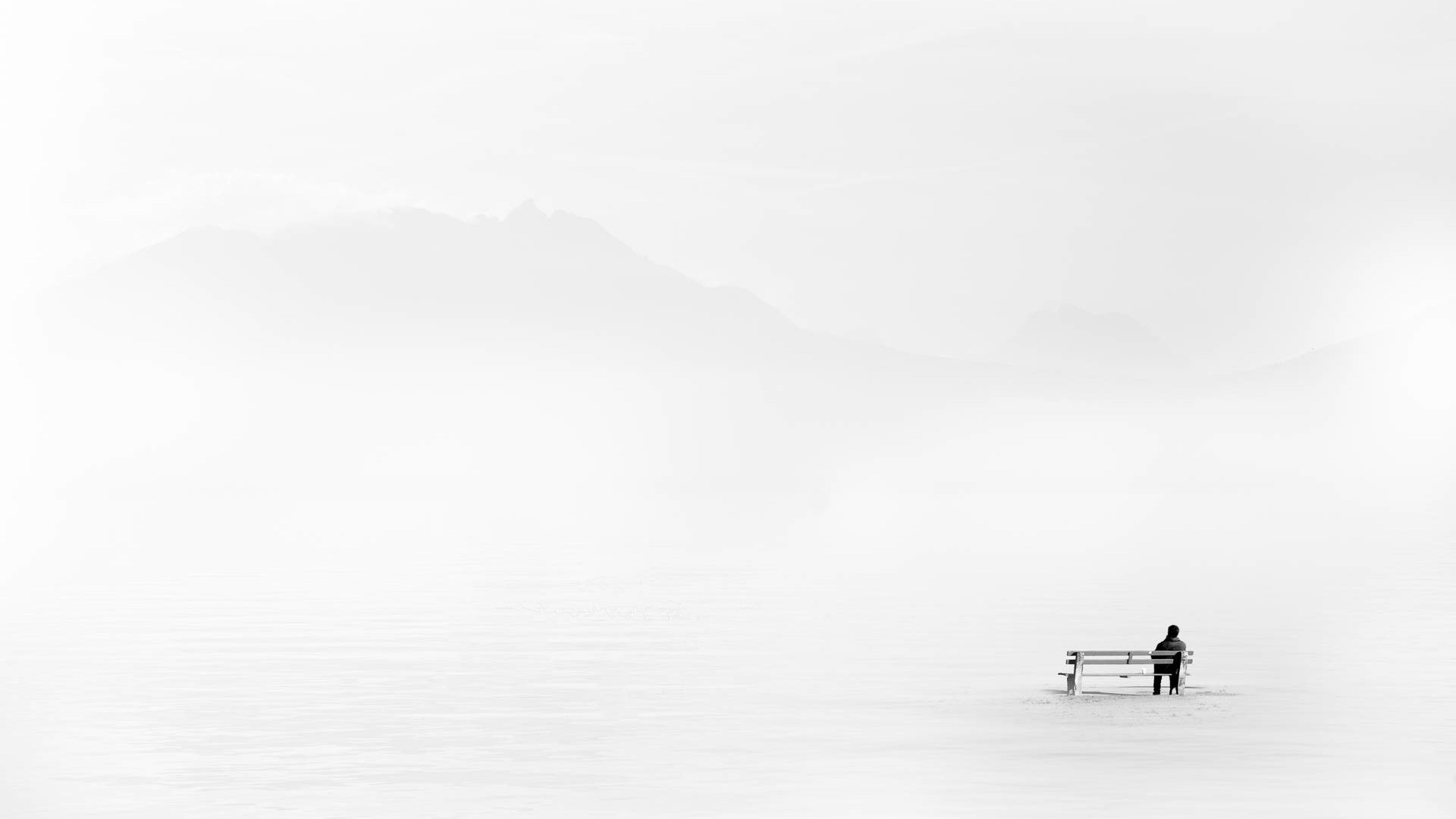 Man sitting on a bench in a foggy winter landscape HD Wallpaper