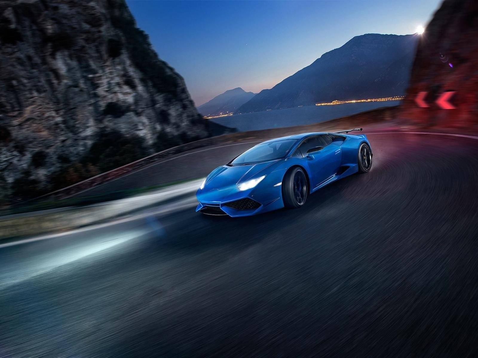 Blue Lamborghini Huracan driving on a winding road at dusk HD Wallpaper