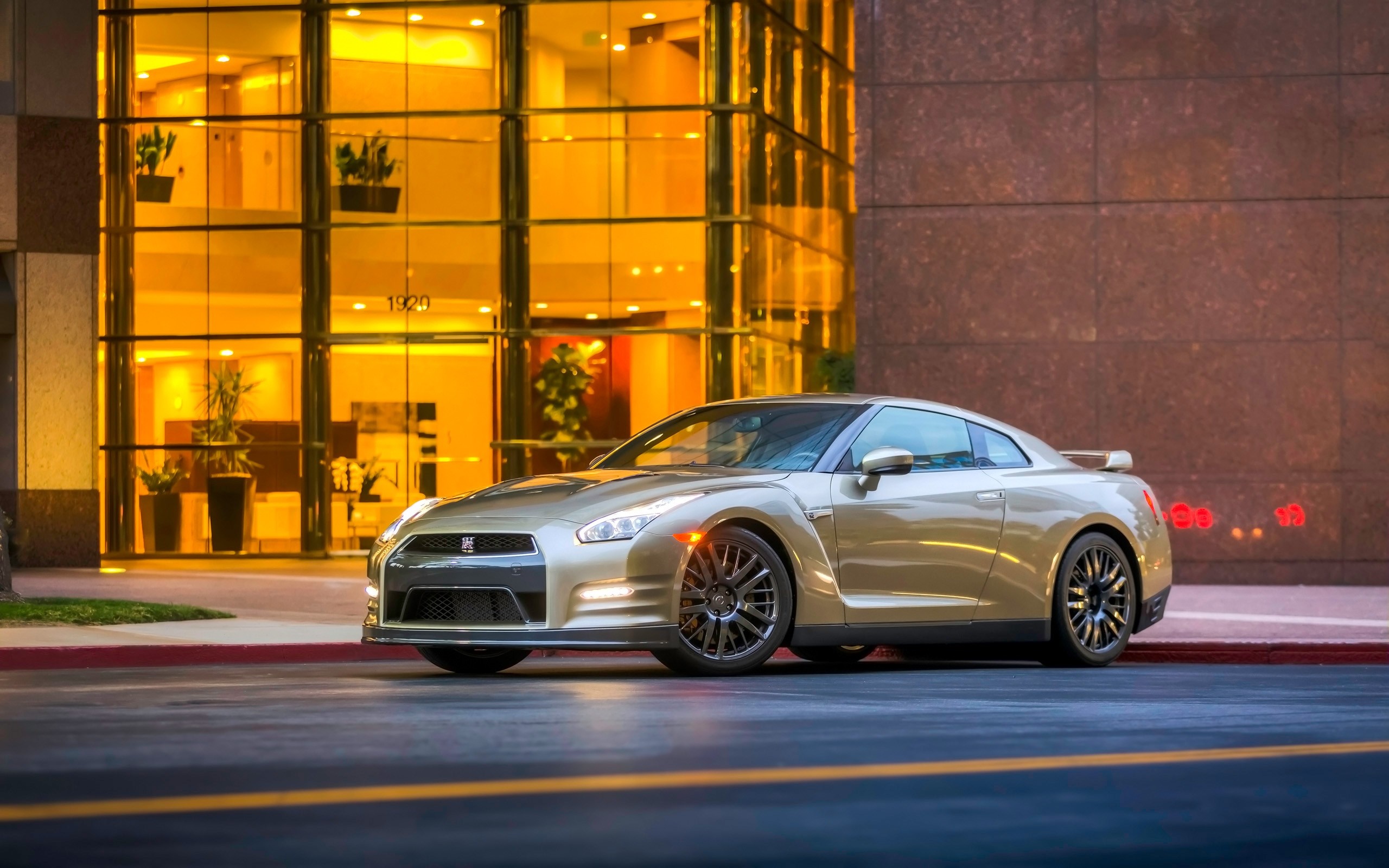 Gold Nissan GT-R parked in front of a modern building HD Wallpaper