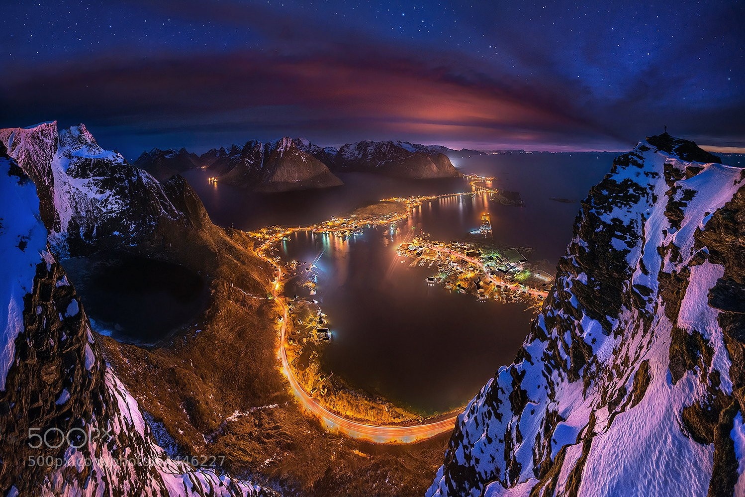 Aerial view of a Norwegian village at night with mountains and stars HD Wallpaper