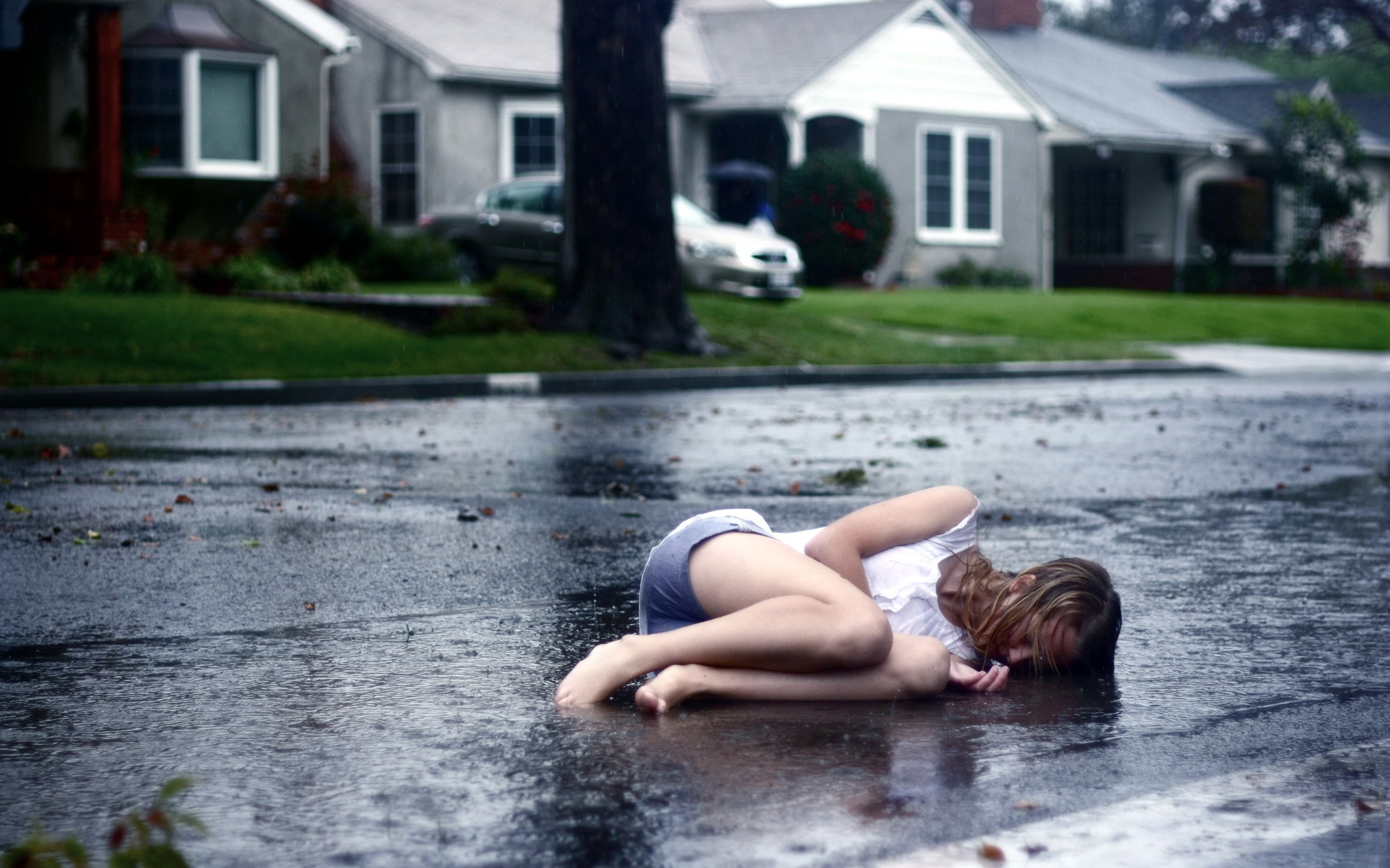 Woman lying in the rain on a wet road HD Wallpaper