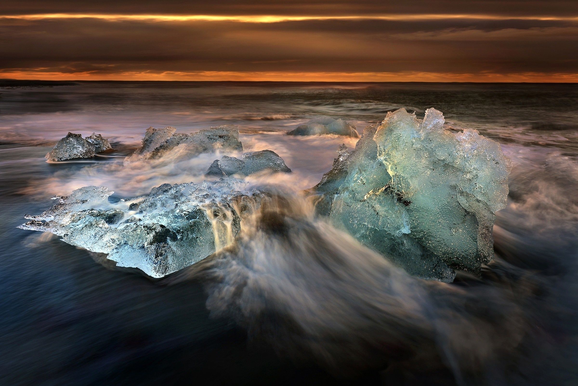 Icebergs on a black sand beach at sunset HD Wallpaper