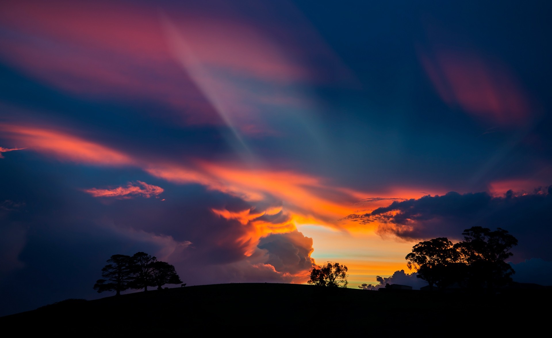 Sunset with crepuscular rays over silhouetted hills HD Wallpaper