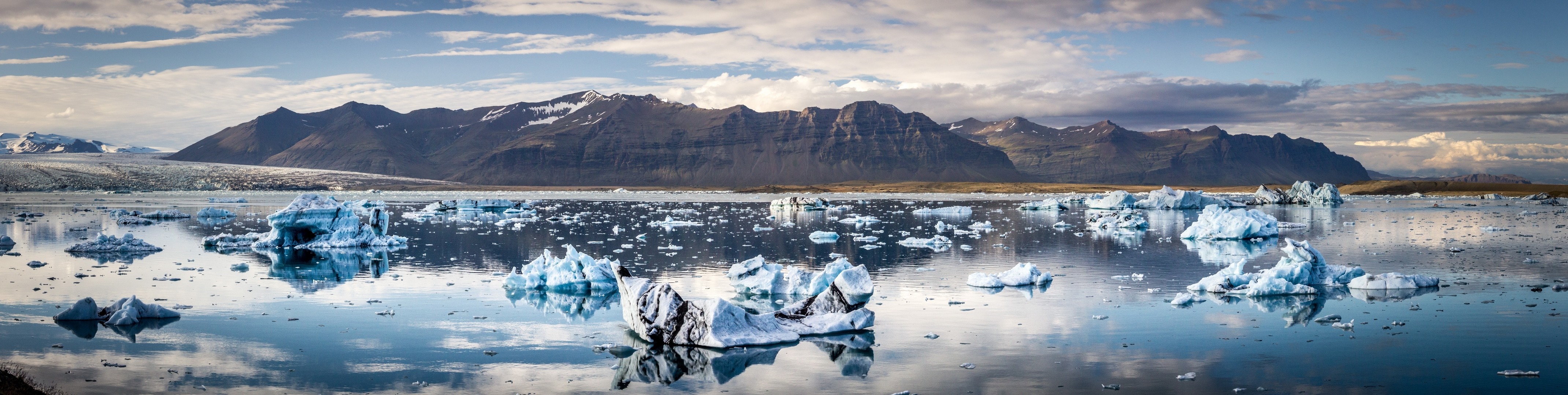 Icebergs floating in a glacial lake with mountains in the background HD Wallpaper