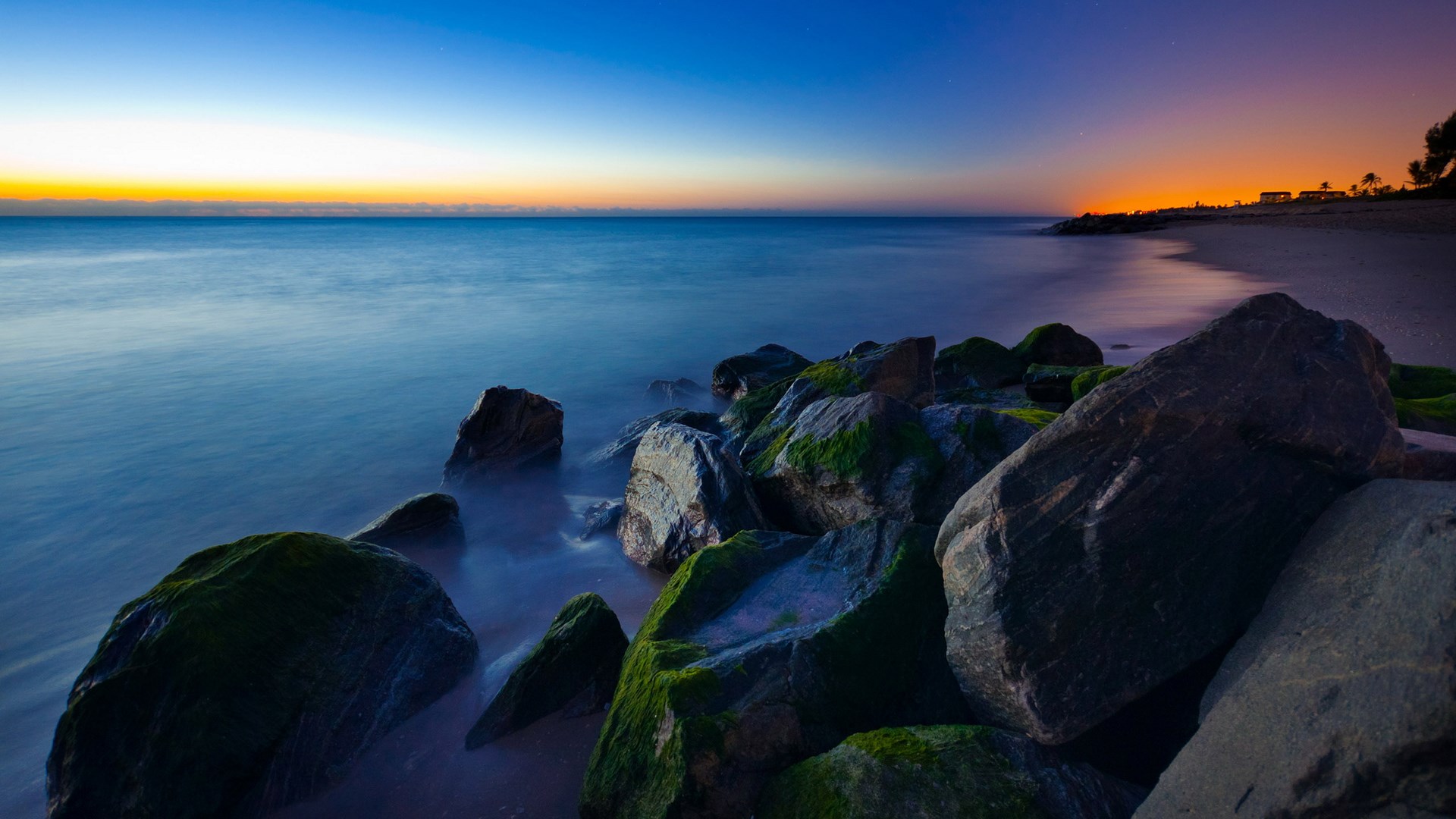 Rocky beach at sunset with calm ocean waves HD Wallpaper