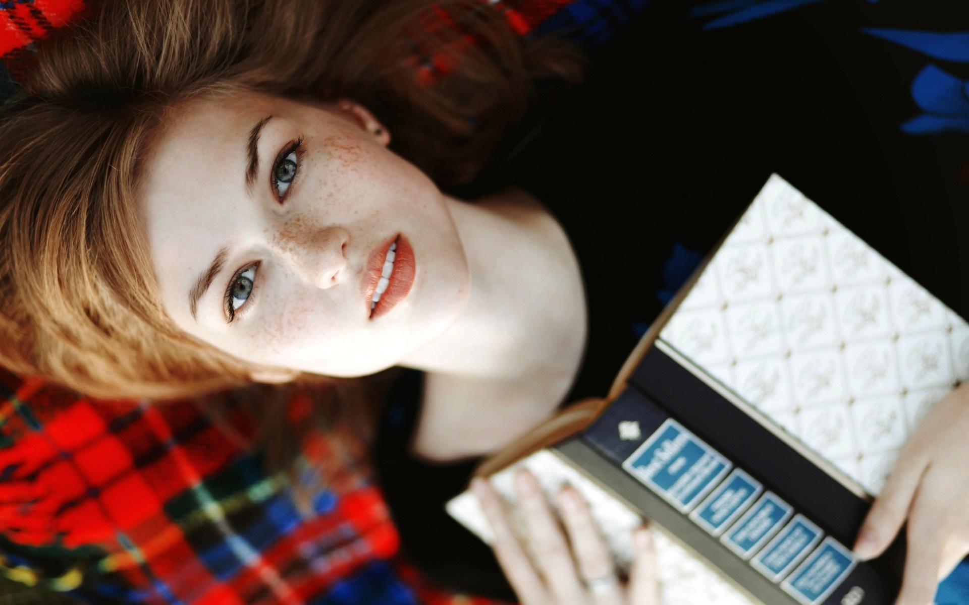 Woman with freckles lying down with a book HD Wallpaper