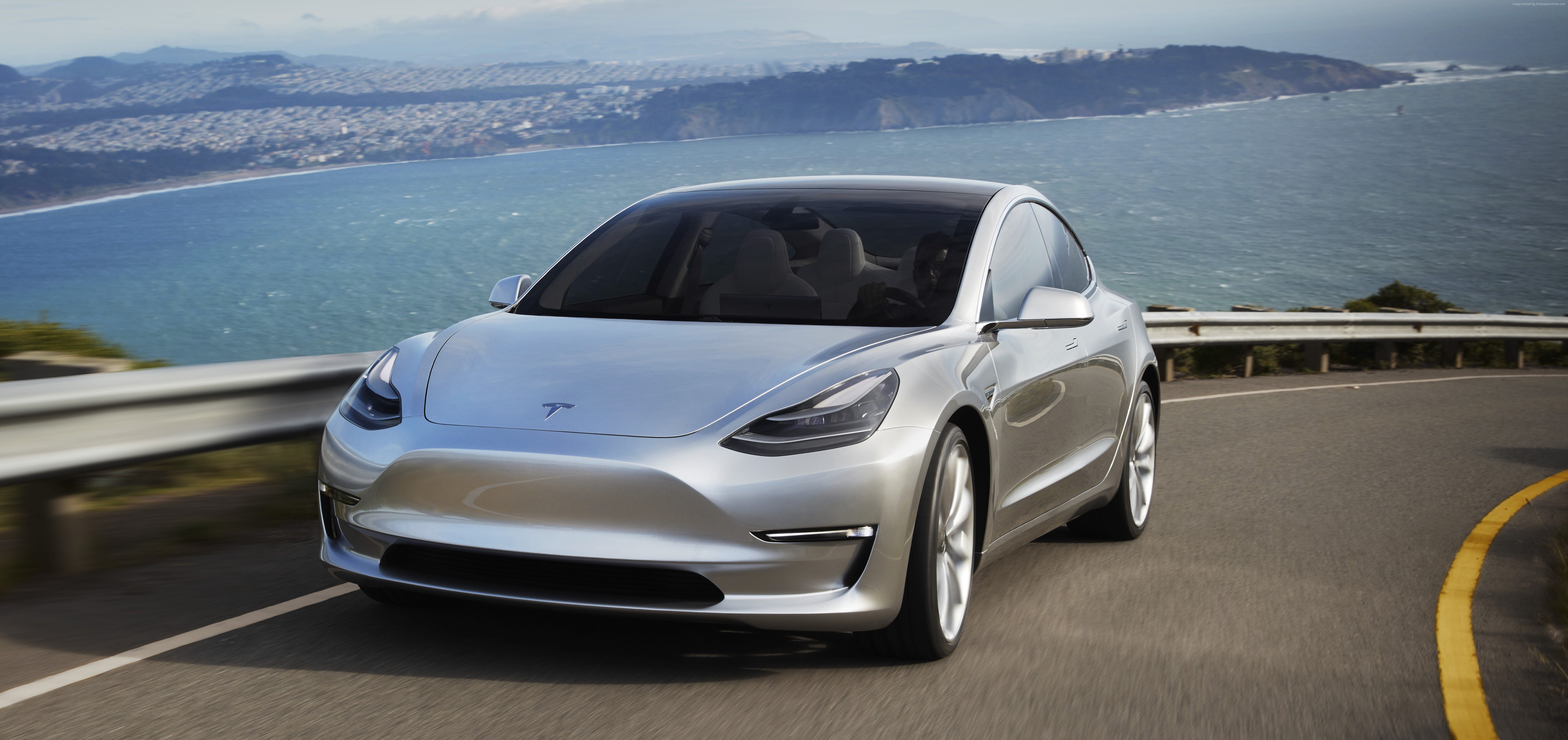 Silver Tesla Model 3 Prototype driving on a coastal road HD Wallpaper