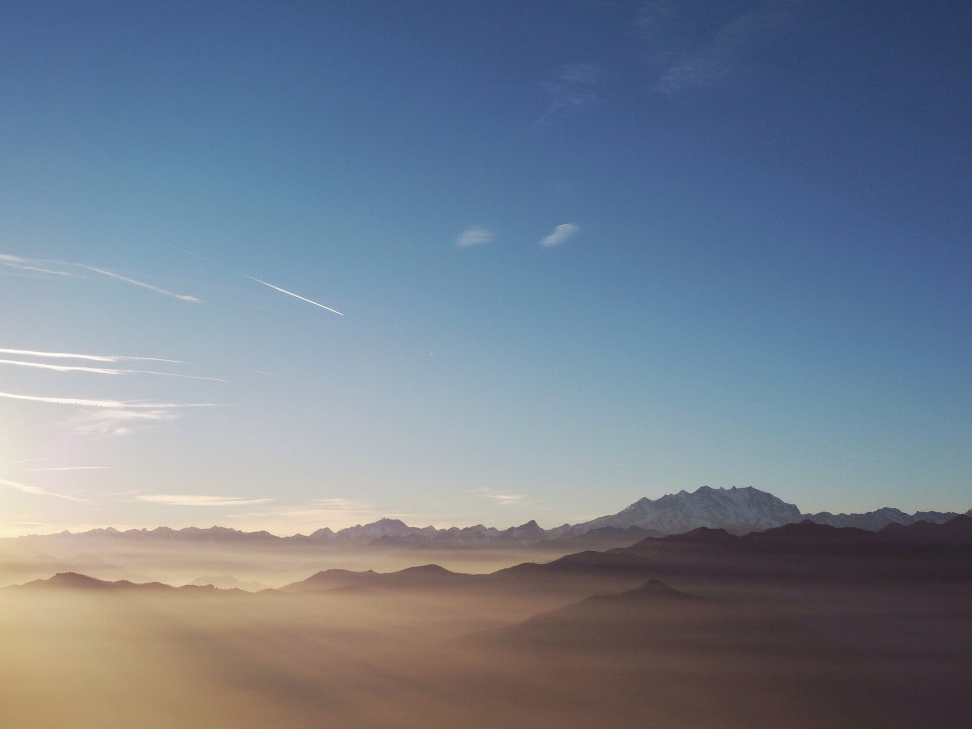 Mountain range shrouded in mist under a clear blue sky HD Wallpaper