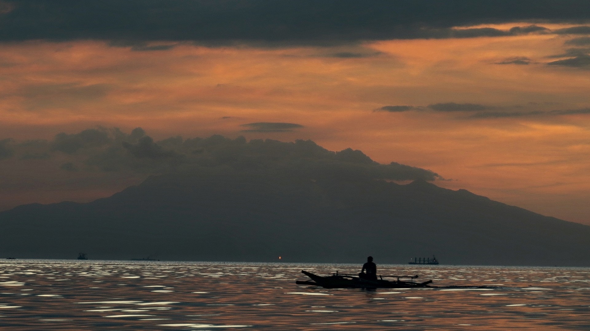 Silhouette of a person in a boat at sunset over the sea HD Wallpaper
