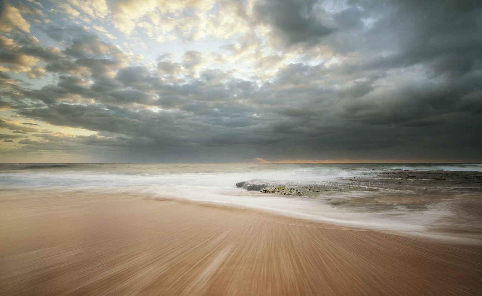 Ocean waves crashing on a sandy beach at sunset HD Wallpaper