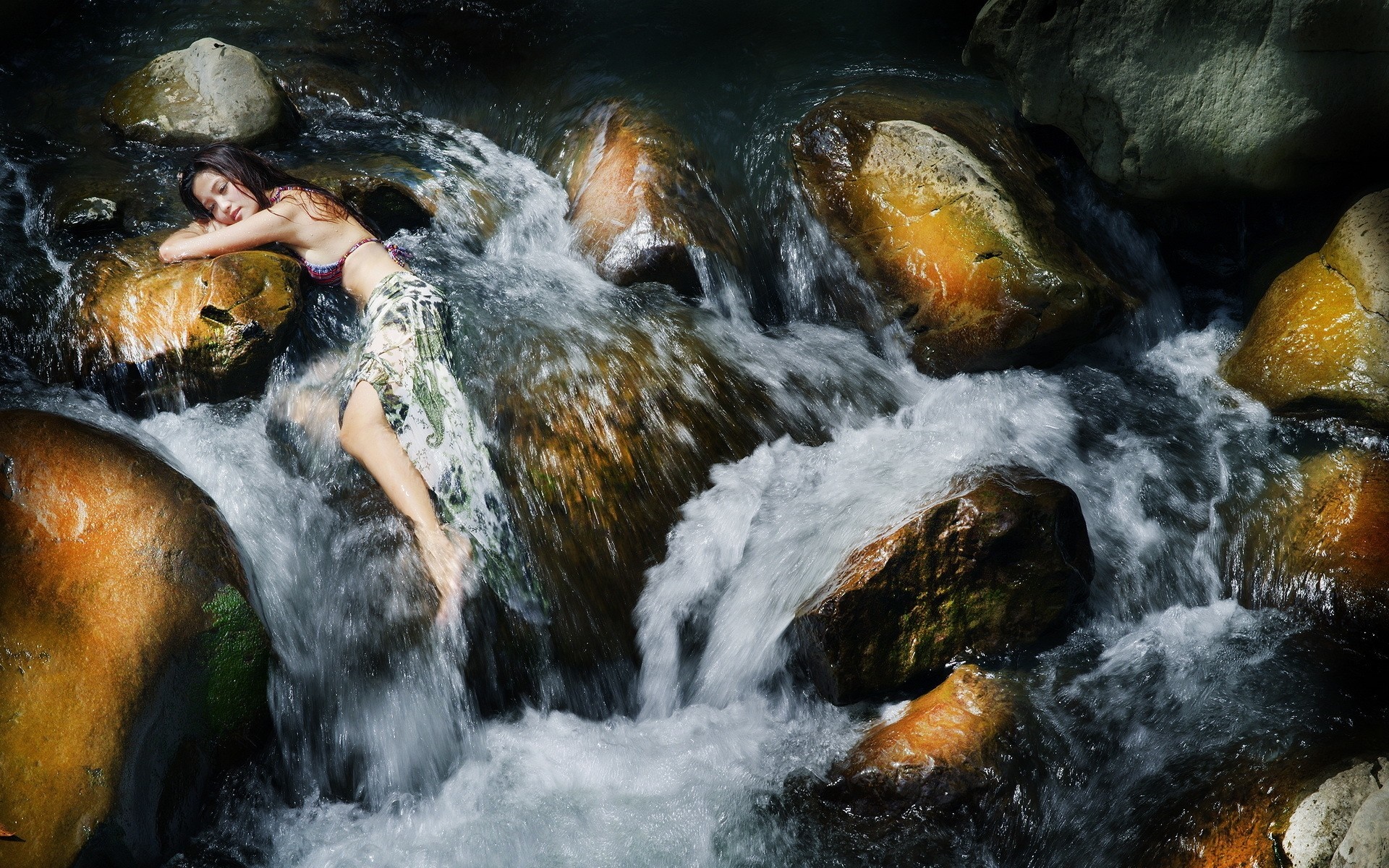 Woman lying on rocks in a stream HD Wallpaper