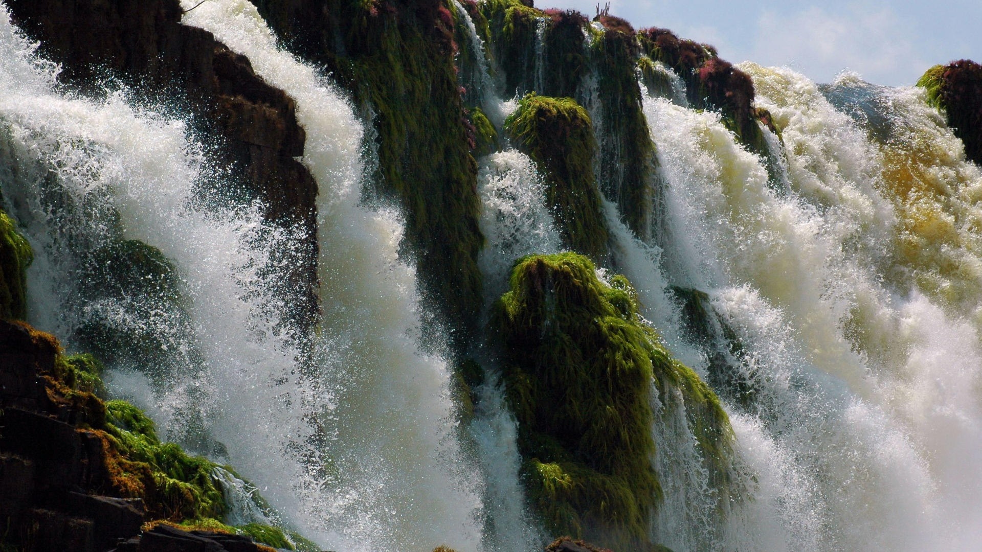 Waterfall cascading over moss-covered rocks HD Wallpaper