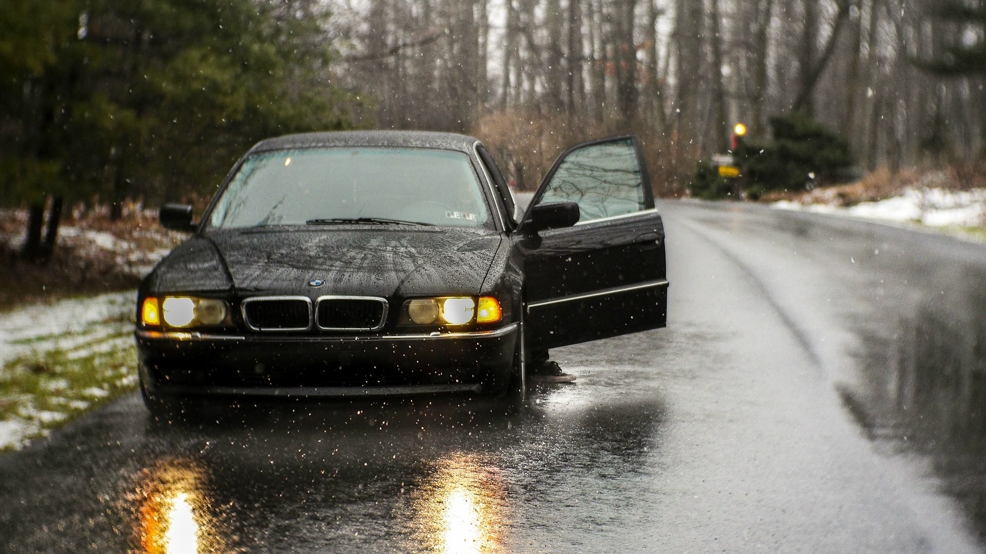 Black BMW 740 parked on a wet road in the snow HD Wallpaper