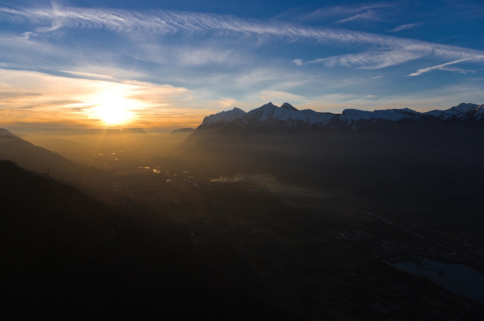 Sunset over a misty mountain valley with snow-capped peaks HD Wallpaper