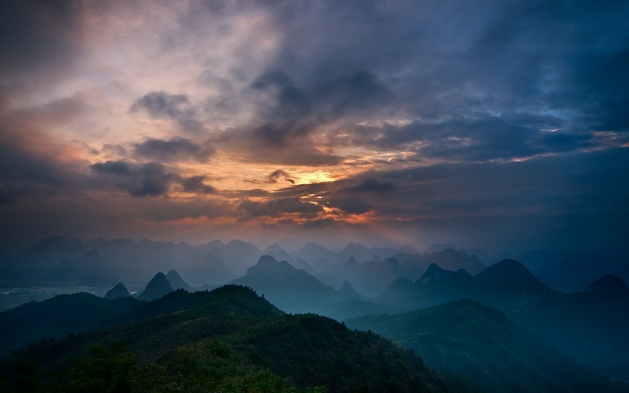 Misty mountains at sunrise with sunbeams through clouds HD Wallpaper