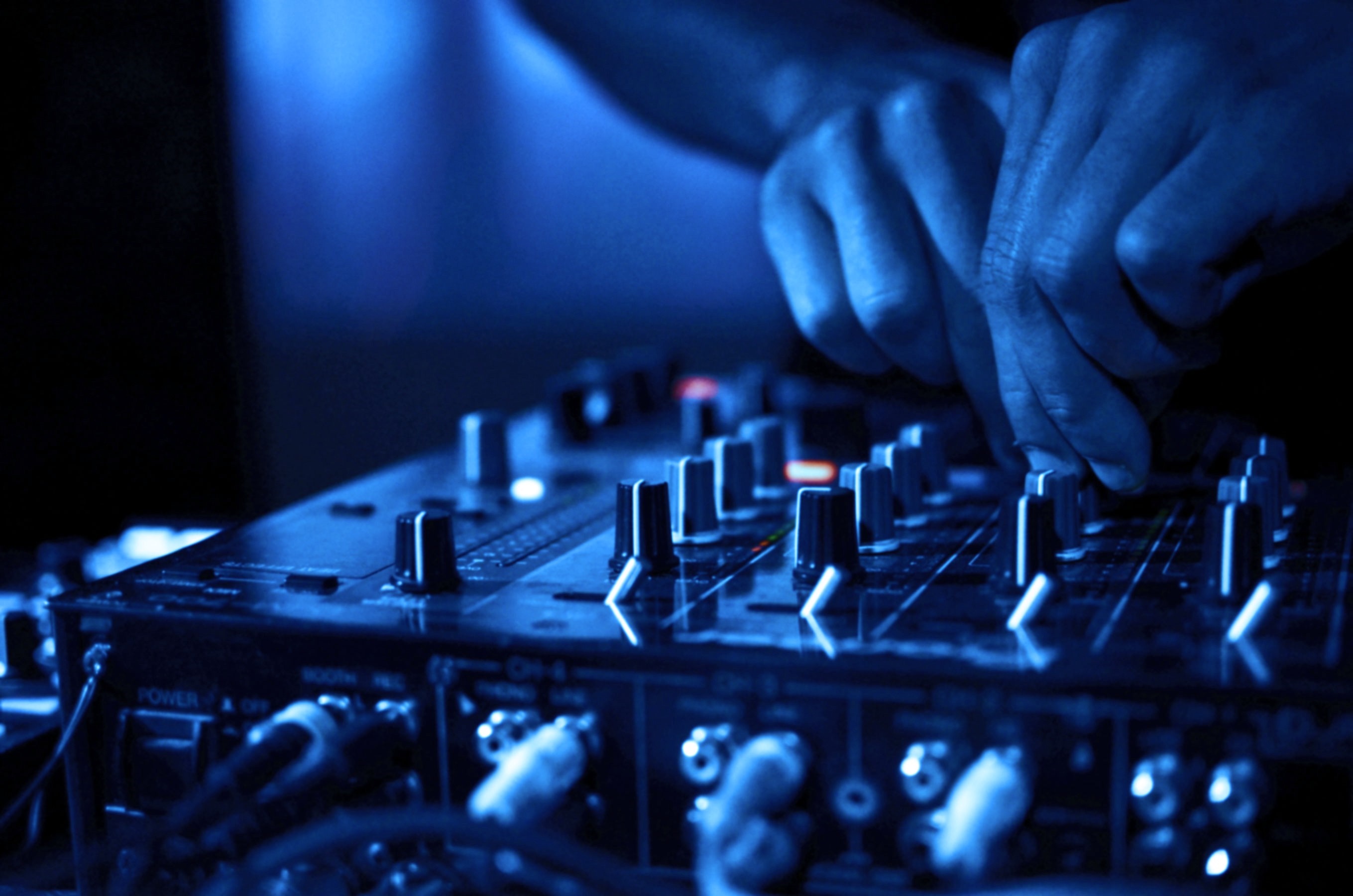 DJ hands mixing music on a blue-lit console HD Wallpaper