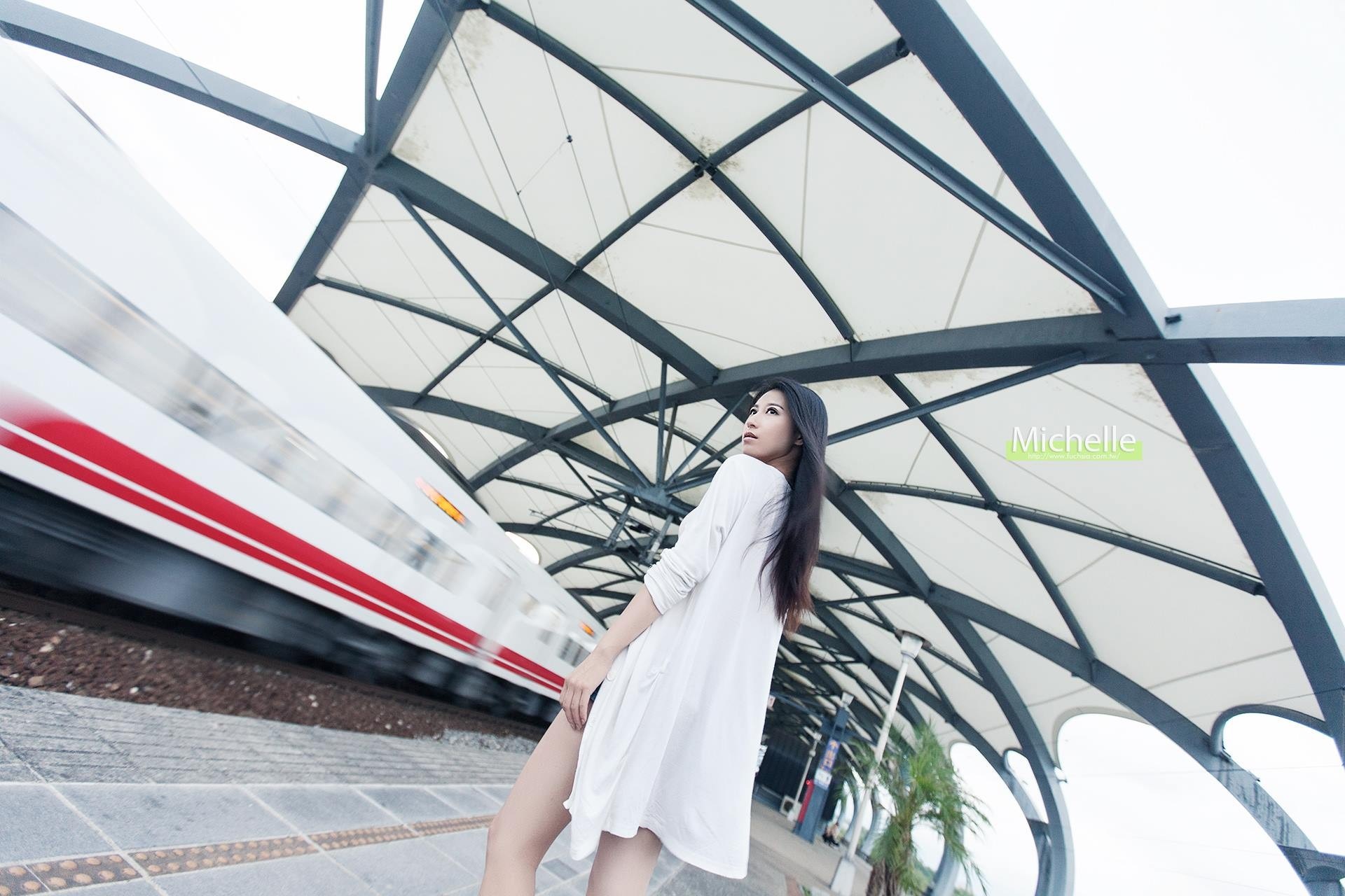 Woman at a train station with a passing train HD Wallpaper